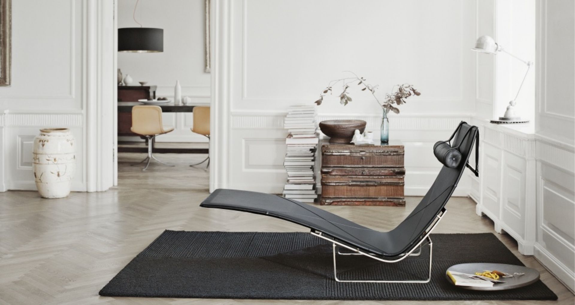 PK24 Liege von Fritz Hansen, schwarzes Leder, Stahlgestell, modernes Wohnzimmer mit Teppich.