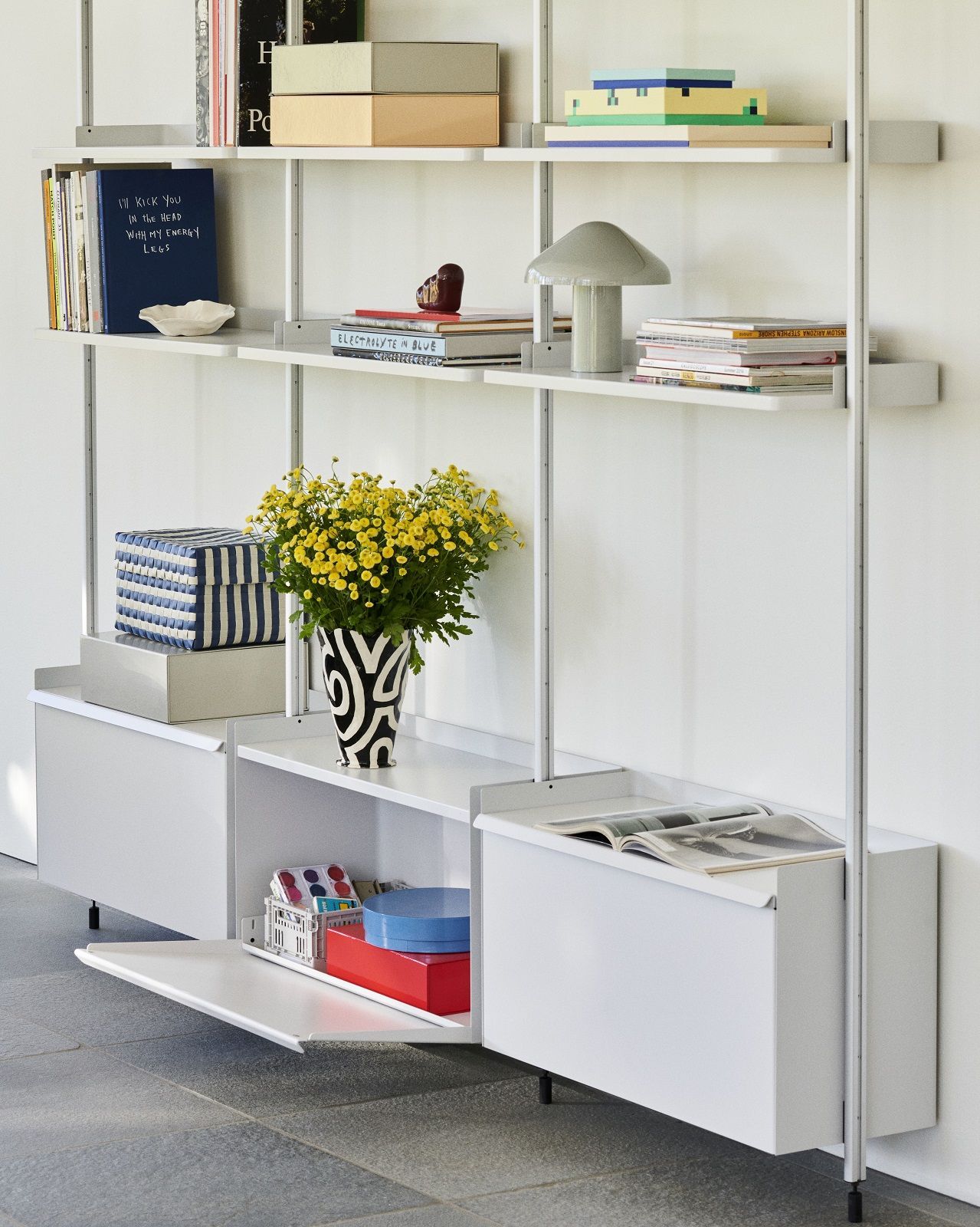 Weißes Hay Pier System Regal mit drei Säulen, Aluminiumrahmen und dekorativen Gegenständen.