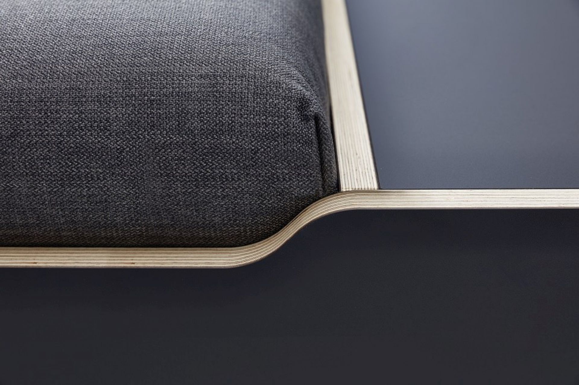 Detailaufnahme vom Maude Bett von Müller Möbelwerkstätten mit grauem Stoffbezug und blauem Nachttisch.