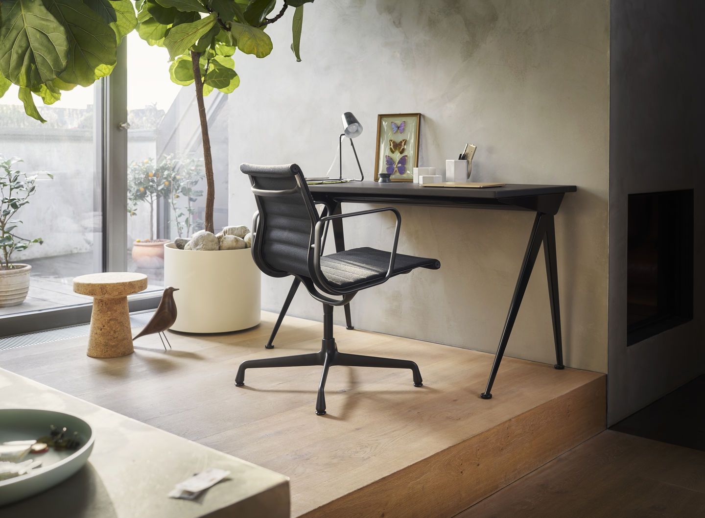 Nahaufnahme eines schwarzen Vitra EA 108 Aluminium Chair Bürostuhls am Schreibtisch in einem modernen Arbeitszimmer.