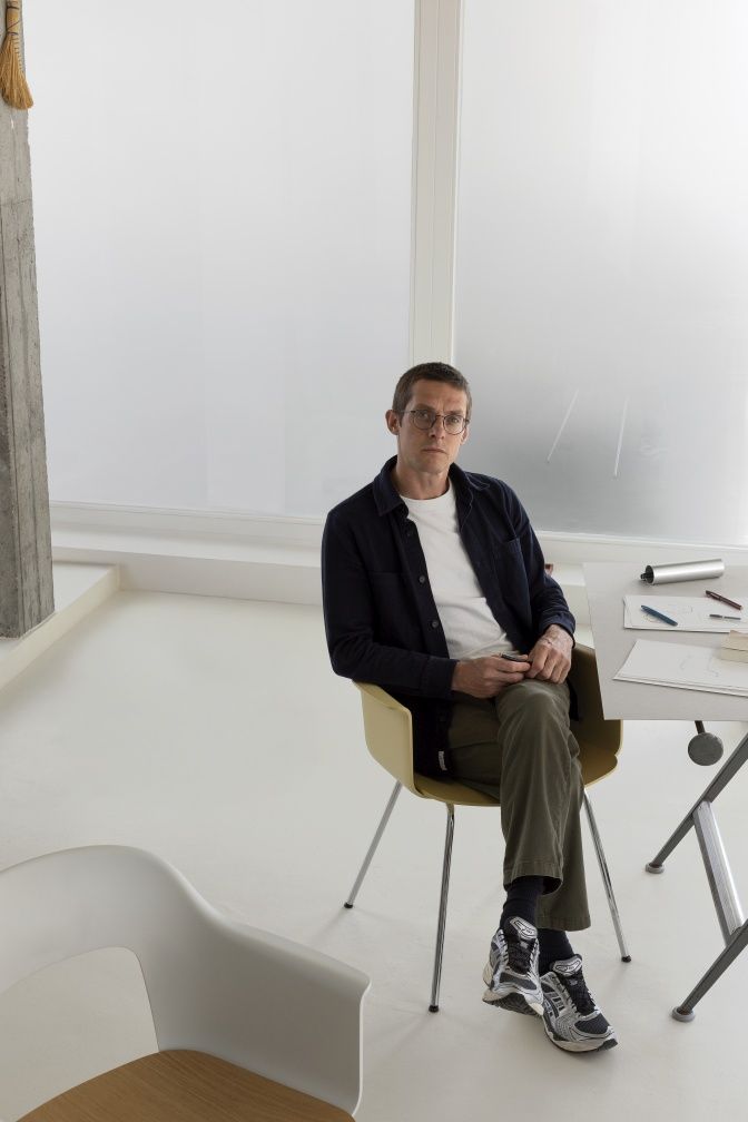 Mann sitzt auf gelbem Hay Layout Armchair 232 Armlehnstuhl mit Chrombeinen in minimalistischem Raum.