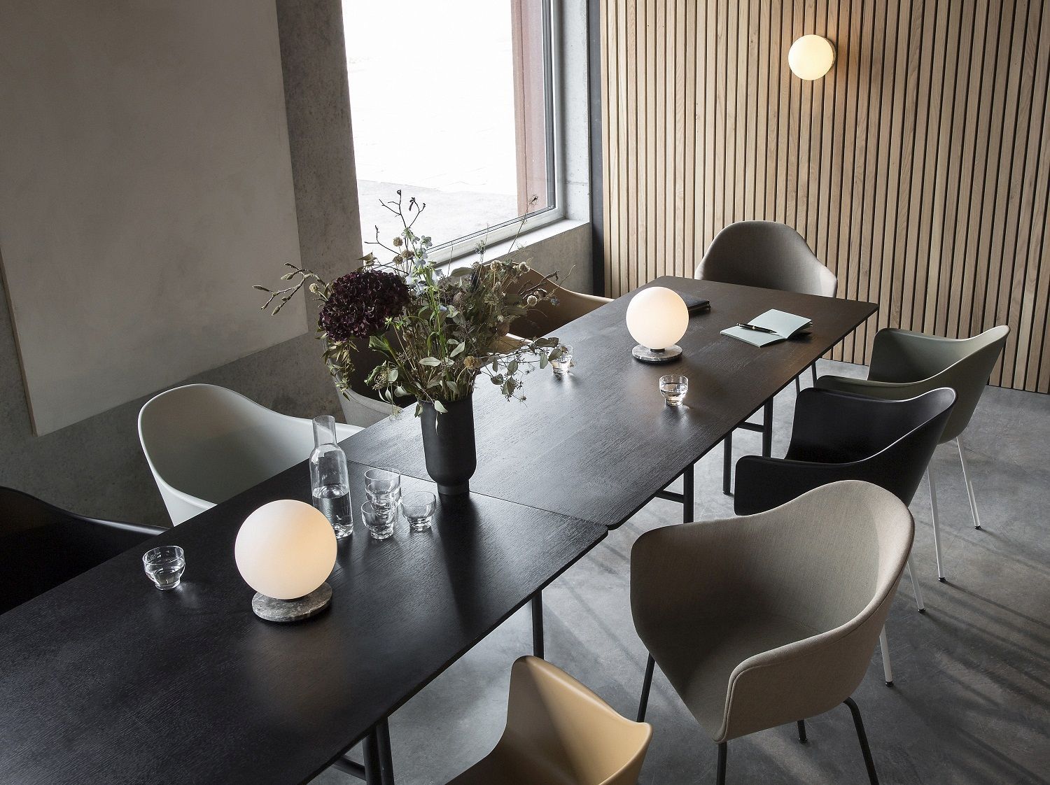 Esstisch-Szene mit Audo Copenhagen Harbour Dining Chairs in verschiedenen Farben und Tischleuchten.