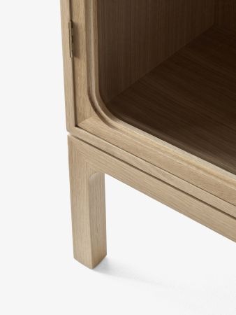 Detailaufnahme des AndTradition Trace Schranks SC88 aus Eiche, Fokus auf Türscharnier und Standbein.