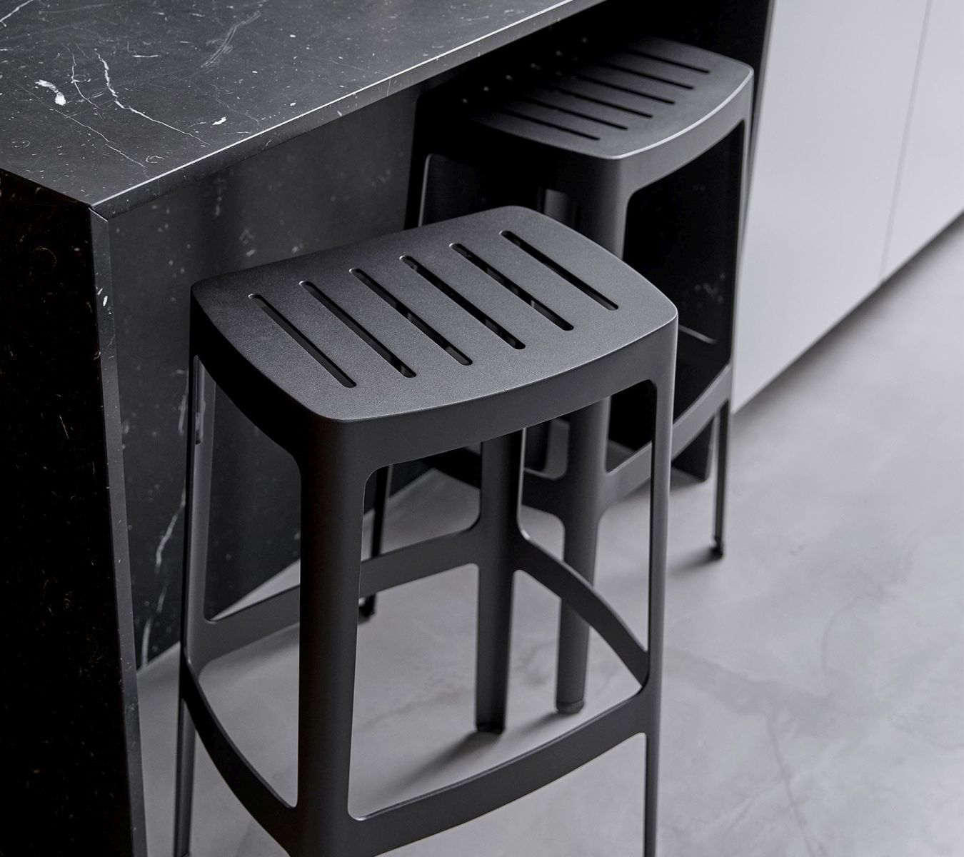 Schwarze Cut Barhocker von Cane-Line, stapelbar, mit schlichtem Design für Küche oder Bar.