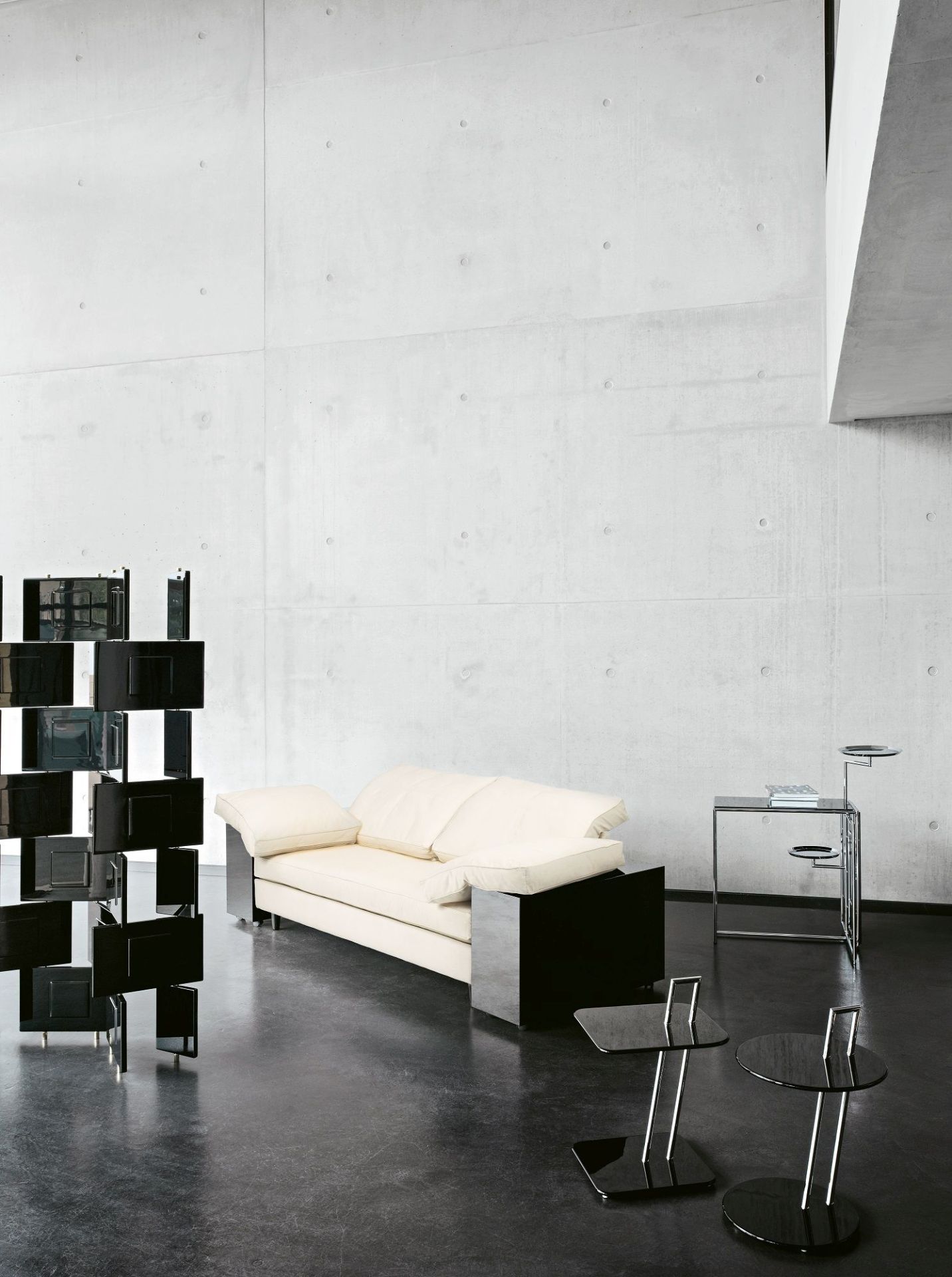 Beige Lota Sofa von Classicon mit schwarzen Akzenten in modernem Interieur mit Betonwand und Designermöbeln.
