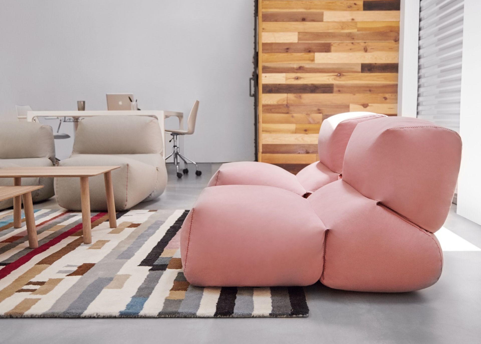 Rosa Grapy Sitzkissen von GAN im modernen Wohnzimmer mit Teppich und Holzwand.