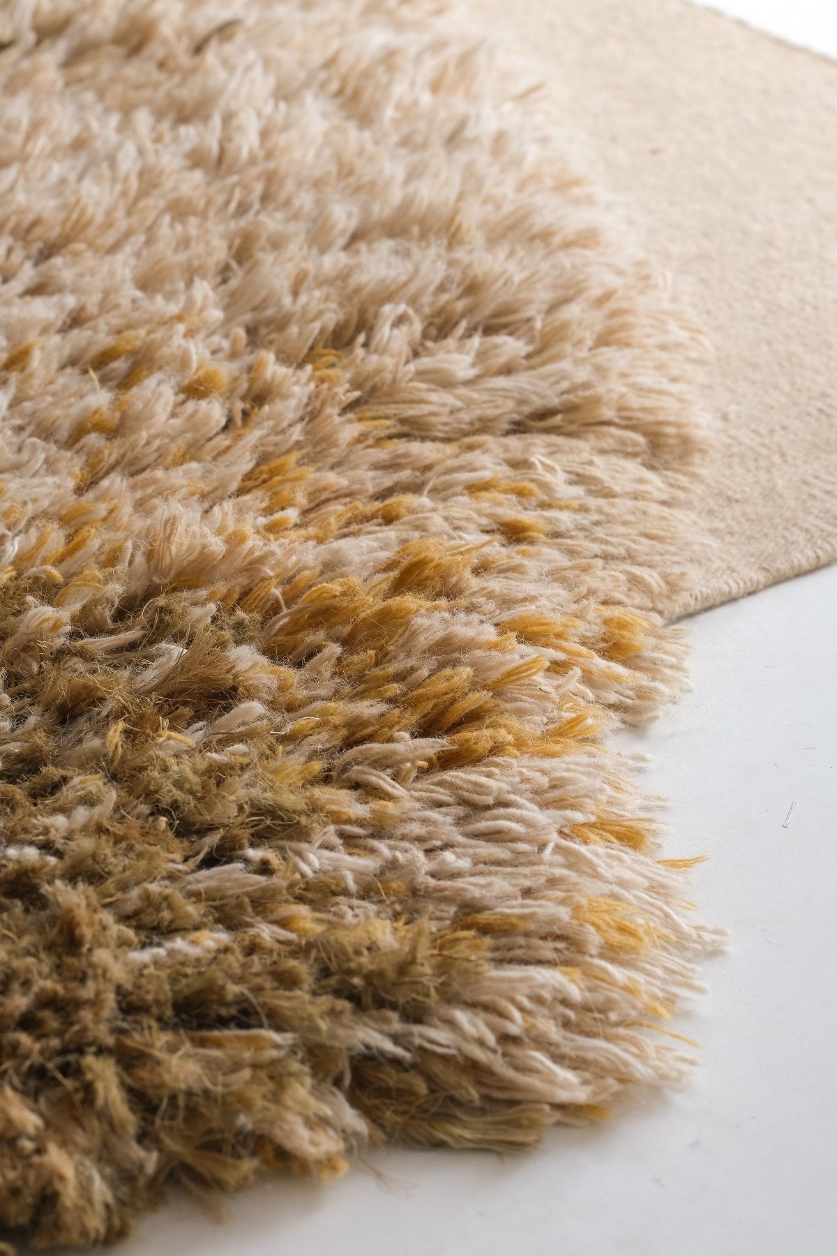 Detailaufnahme des Alga Rug Teppichs von Nanimarquina, ein beiger Wollteppich mit Fransen und Struktur.