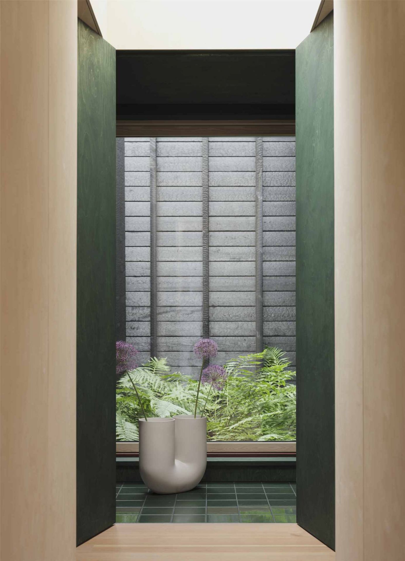 Helle Muuto Kink Vase mit Blumen vor Fenster und grünen Fliesen, modernes Wohndesign.
