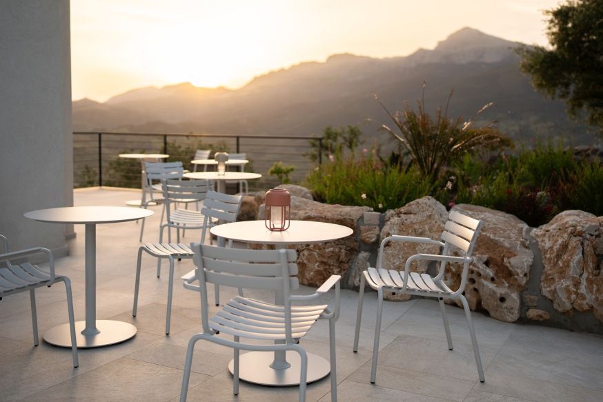 Alua Dining Chair von Houe: Heller Outdoor Stuhl aus Metall auf einer Terrasse.