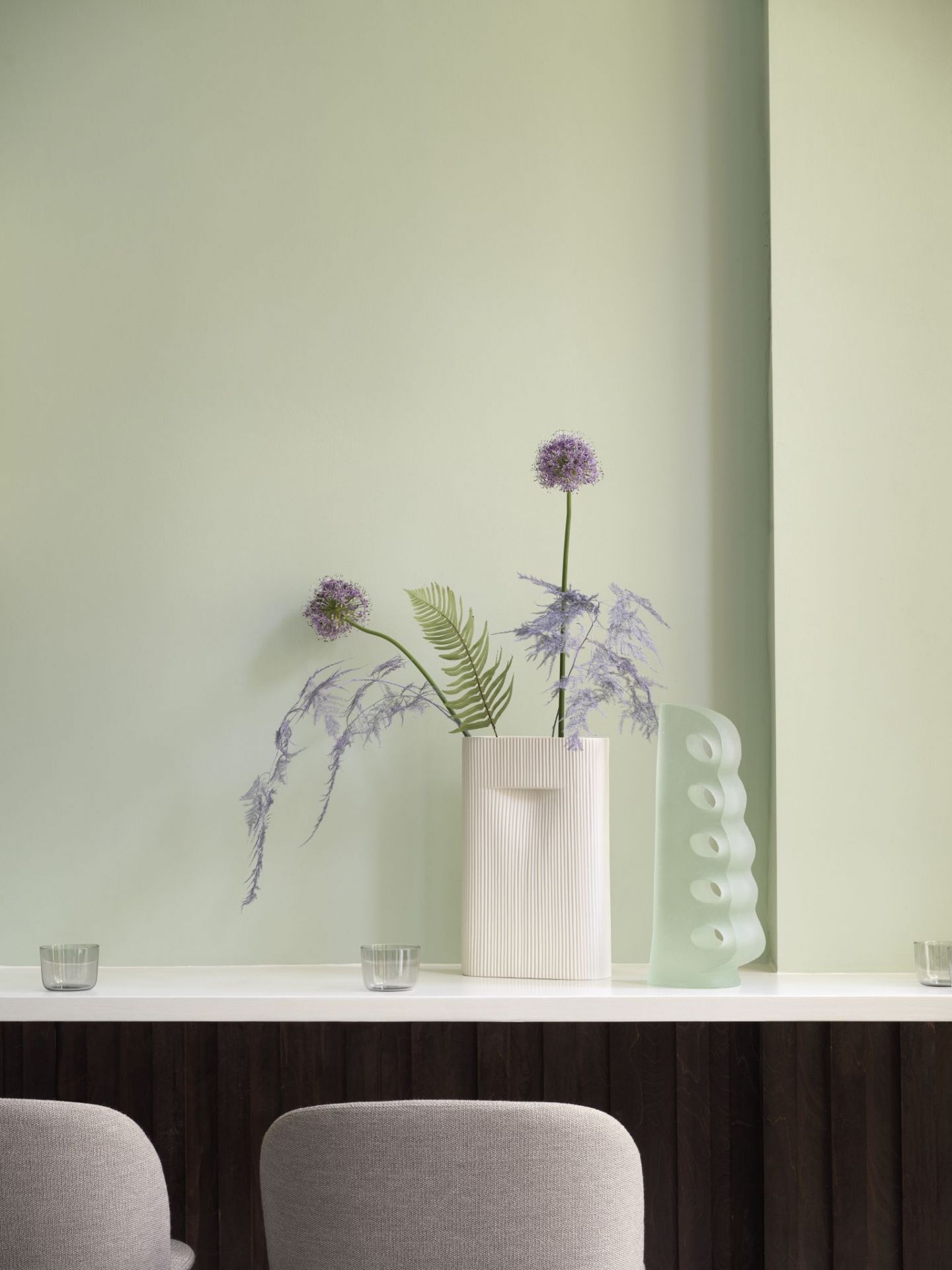 Beige Ridge Vase von Muuto mit Blumen und dekorativer Glasvase auf Regal.