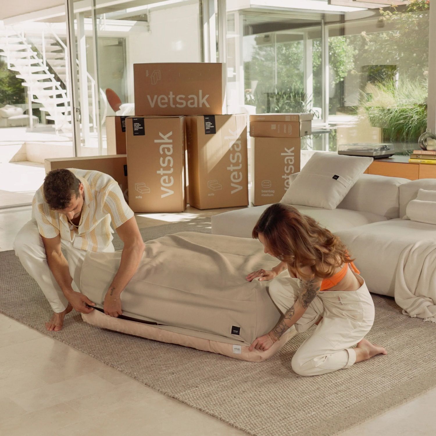 Mann und Frau montieren vetsak Sofa Set 08 Daybed, beige Sitzsack-Elemente und Kartons im Wohnzimmer.