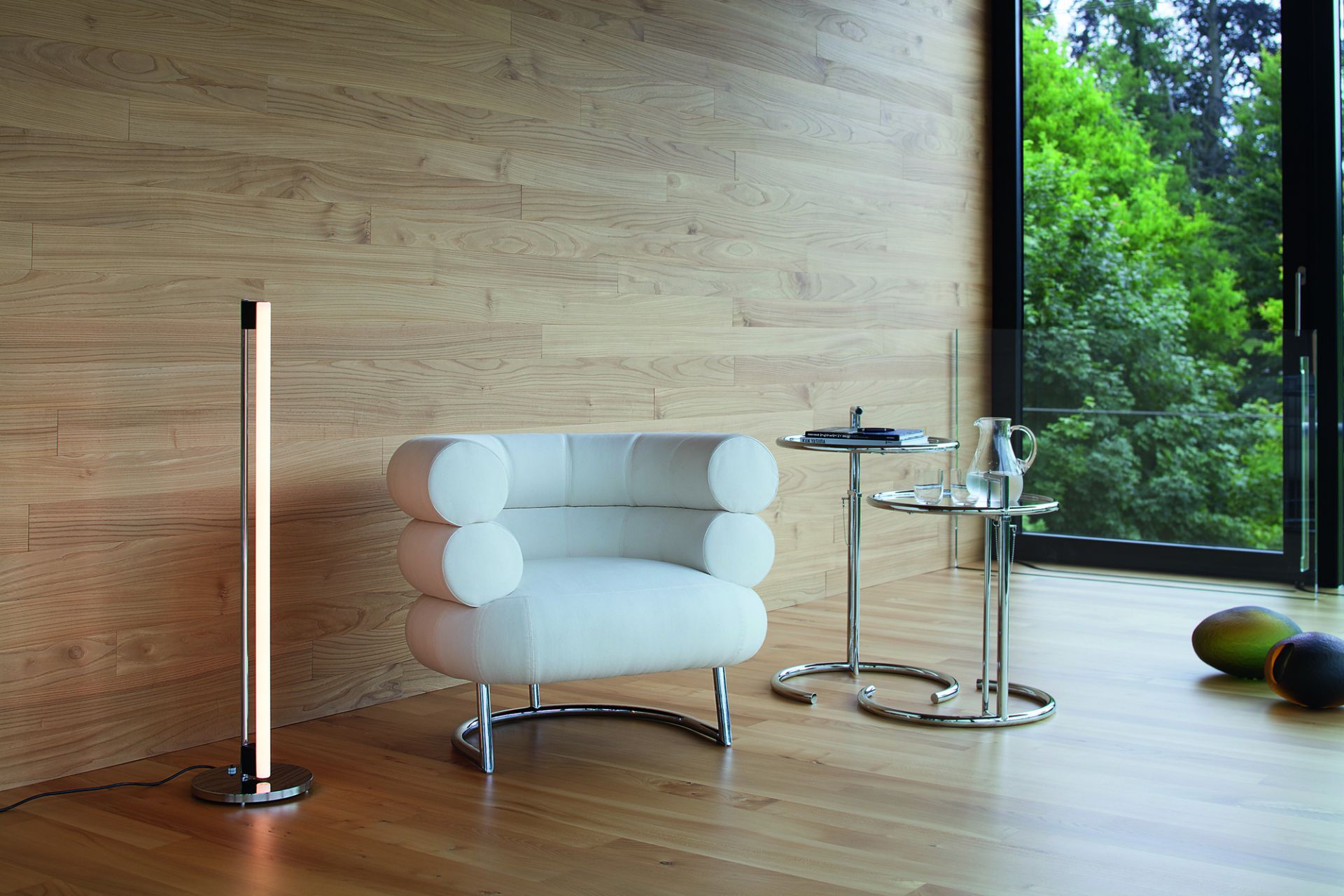 Moderner Wohnraum mit ClassiCon E1027 Beistelltisch, verstellbar, neben Sessel und Stehlampe auf hellem Holzboden.