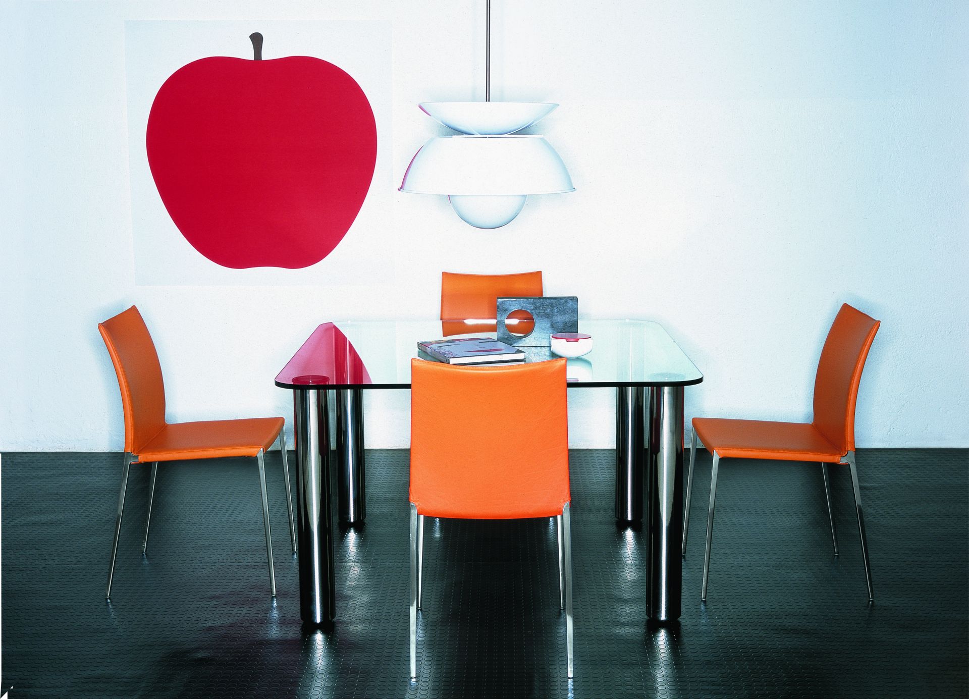 Esszimmer mit Zanotta Lia Stühlen in Orange und einem Tisch mit Glasplatte und Chrombeinen.