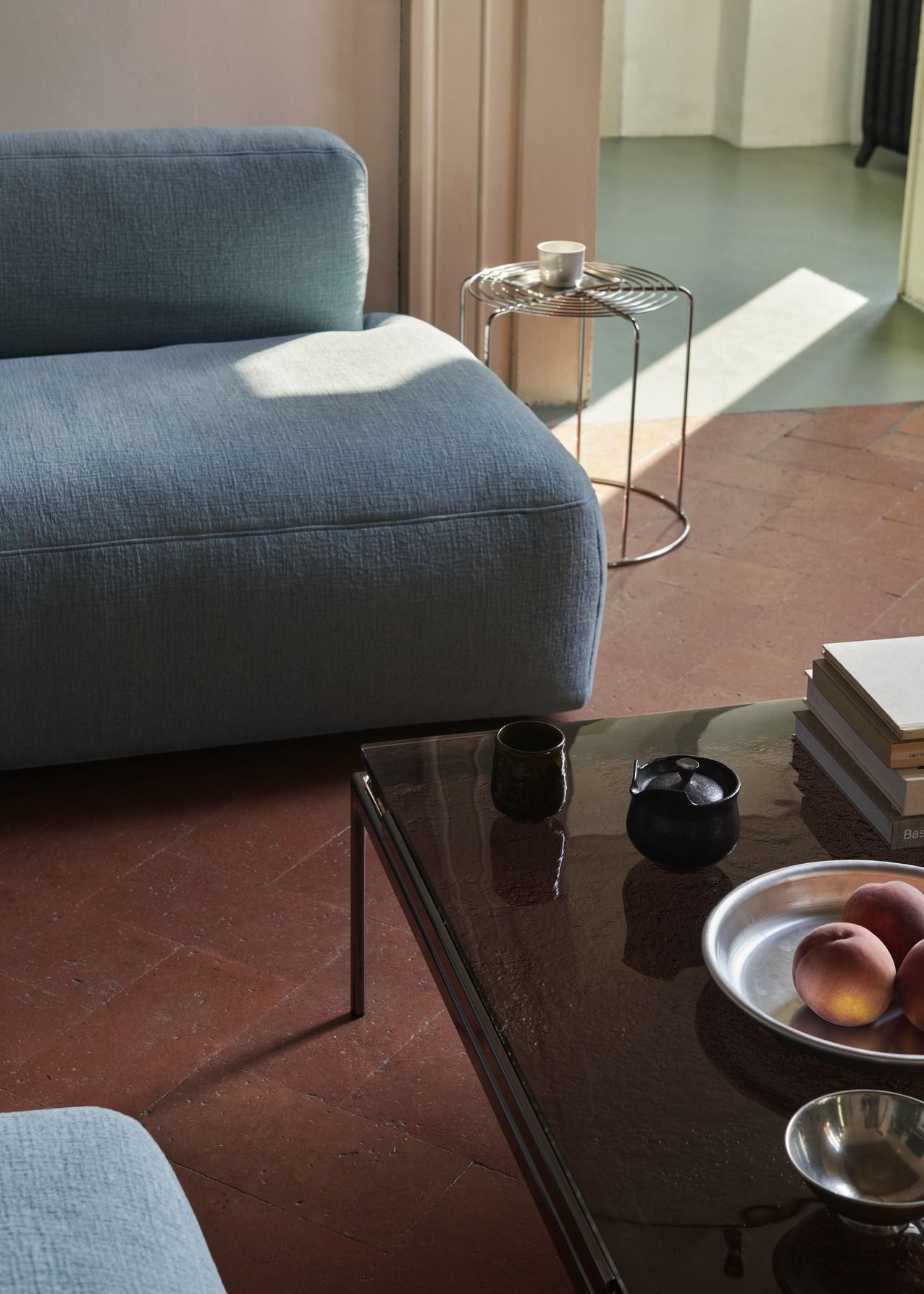 AndTradition Wire Stool VP11 als Beistelltisch neben einem blauen Sofa in einem stilvollen Wohnzimmer.