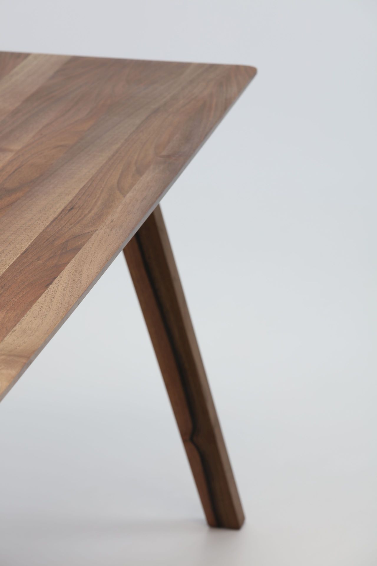 Detailaufnahme vom Monk Tisch von Prostoria, Tischplatte aus Nussbaumholz mit einem schrägen Tischbein.