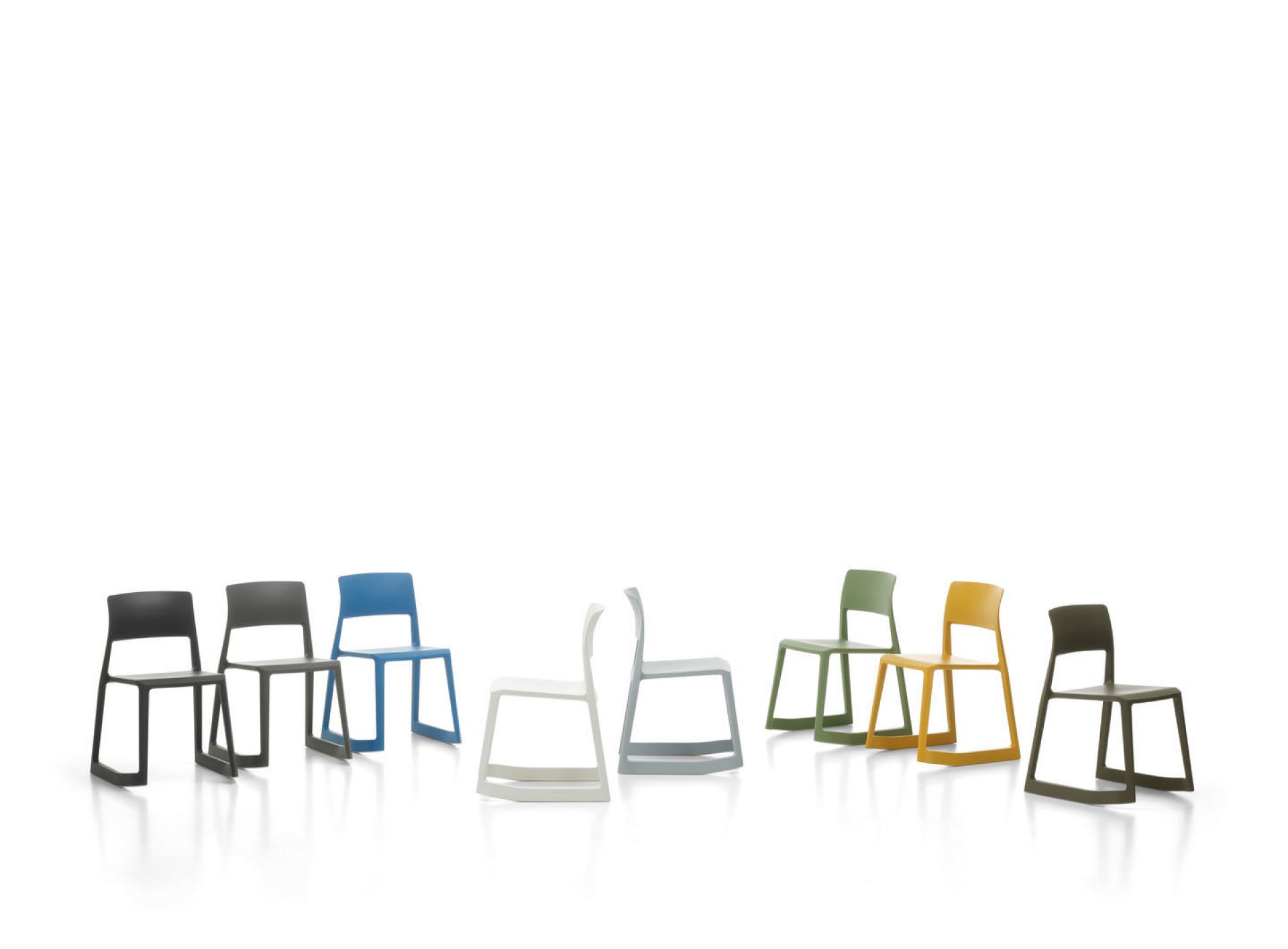 Vitra Tip Ton RE Stühle aus Kunststoff in verschiedenen Farben aufgereiht auf weißem Hintergrund.
