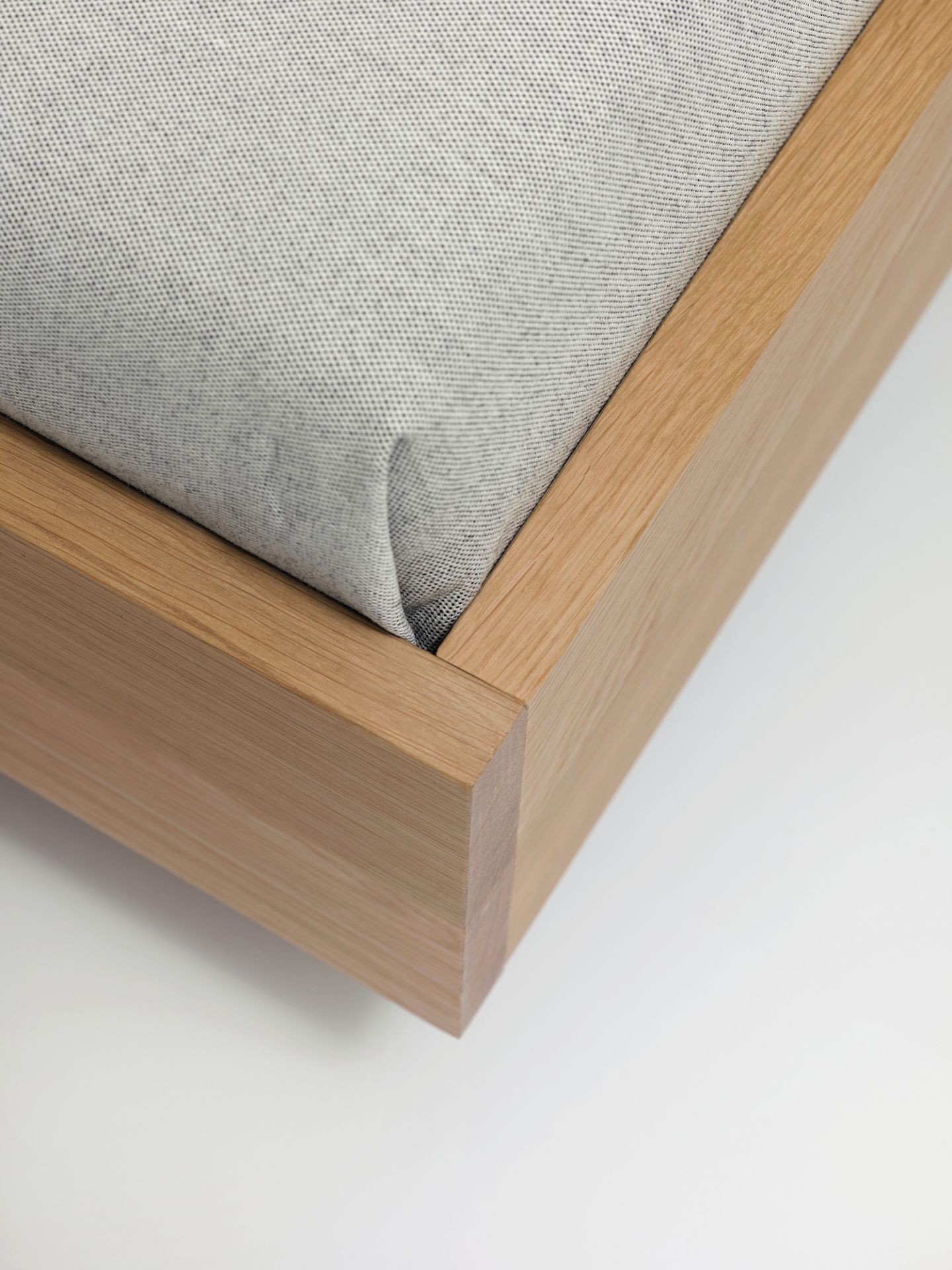Detailaufnahme vom Simple HI Holzbett mit hellgrauem Stoffbezug und minimalistischem Design.
