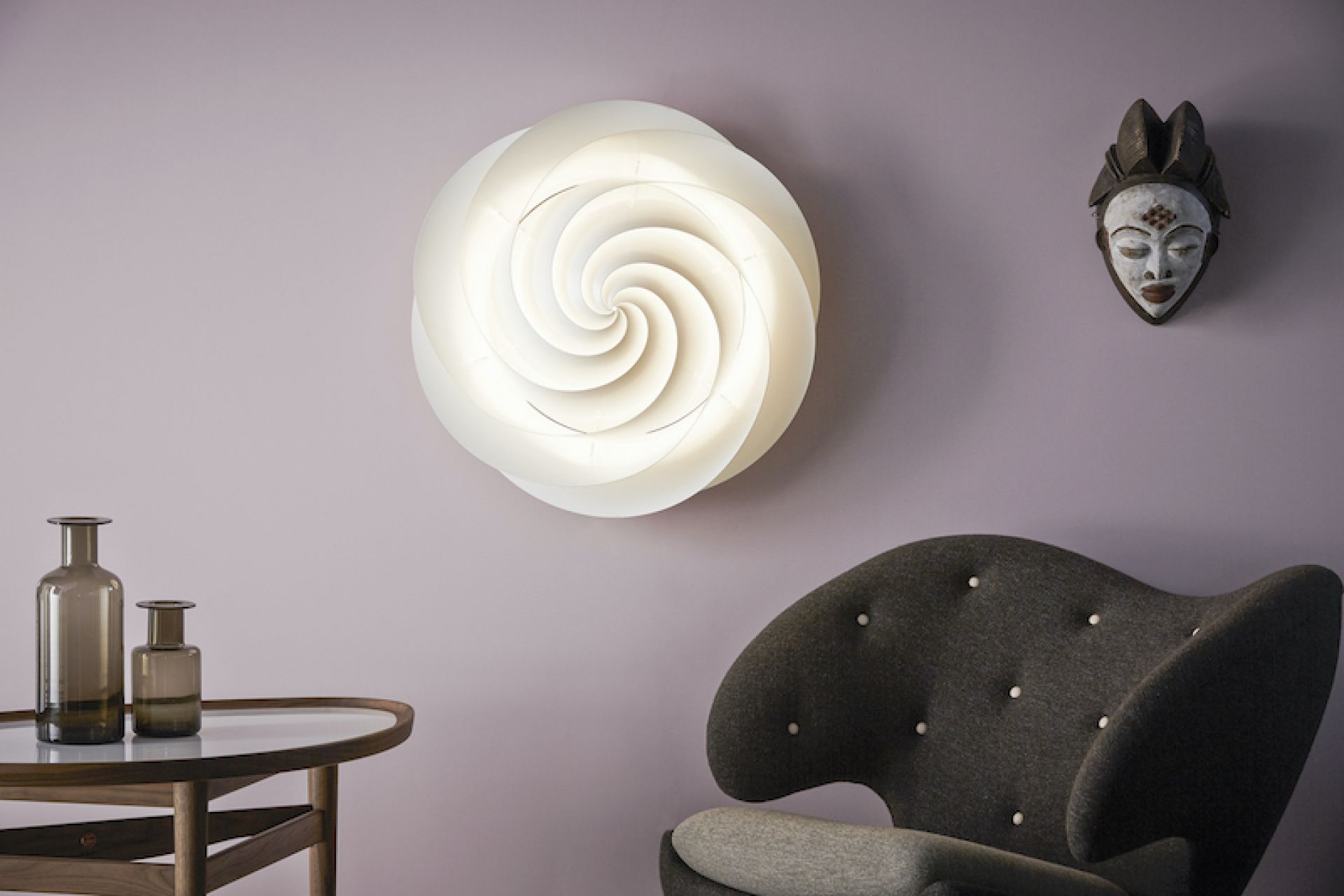 Weiße Swirl Deckenleuchte von Le Klint an lila Wand, spiralförmiges Design, moderne Beleuchtung.