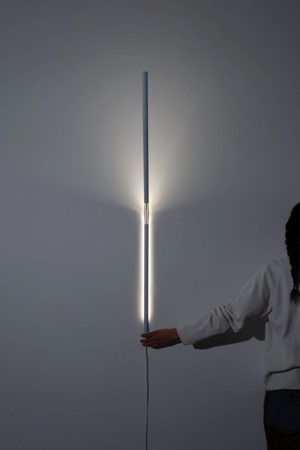 Measure Light Wandleuchte von Ingo Maurer, vertikale LED-Wandlampe mit Hand, modernes Design für Wohnzimmer.