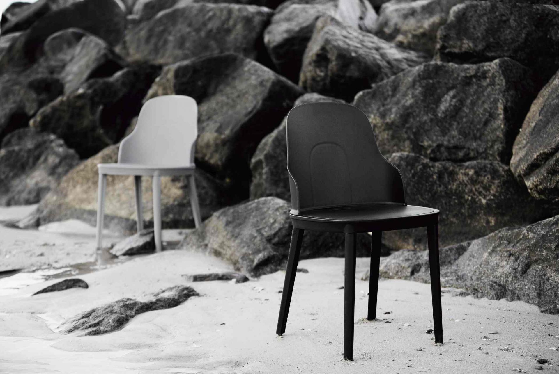 Zwei Allez Stühle von Normann Copenhagen in Schwarz und Grau am Strand vor Felsen.