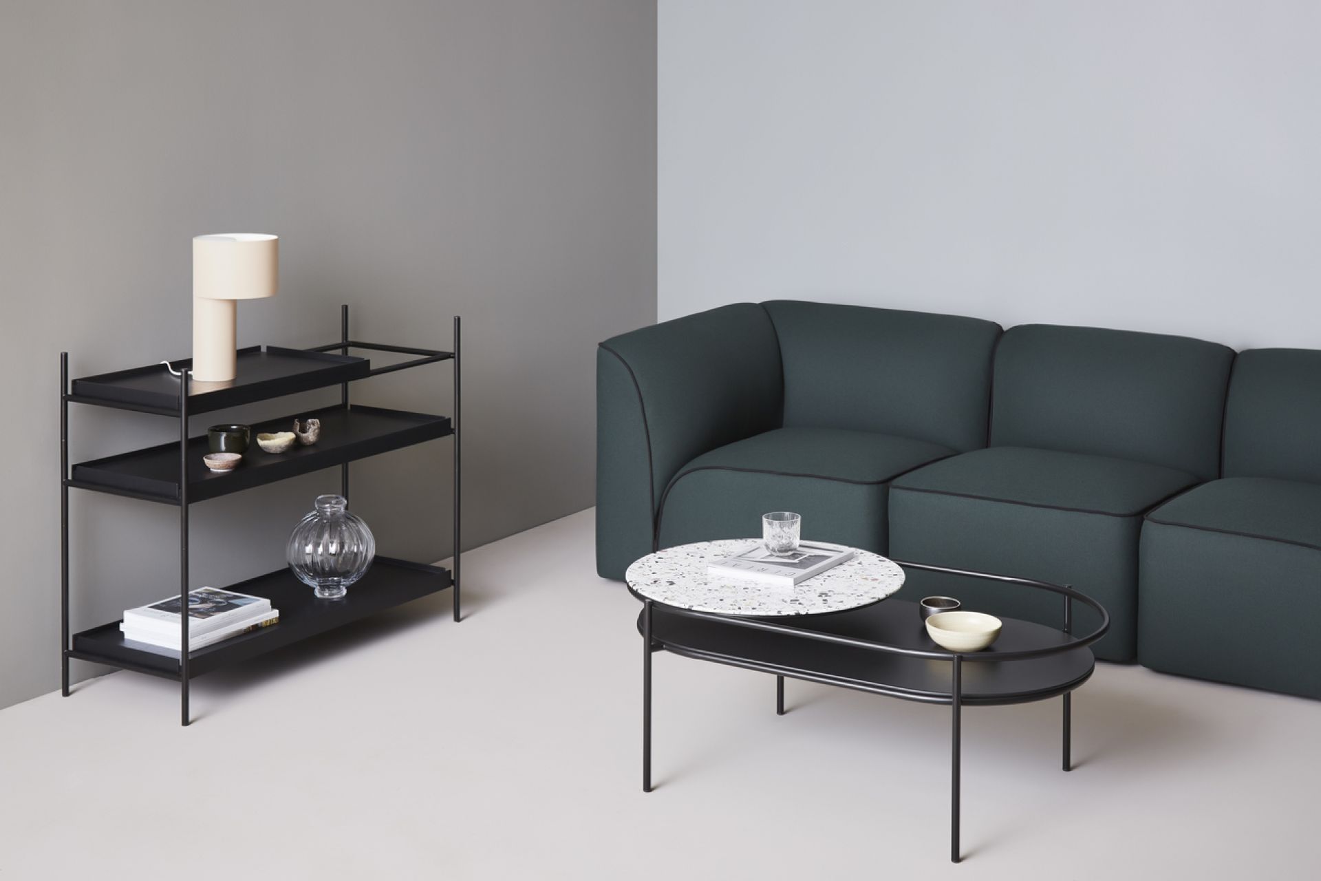 Flora Modulsofa von Woud, dunkelgrün, mit Couchtisch und Regal im modernen Wohnzimmer-Ambiente.