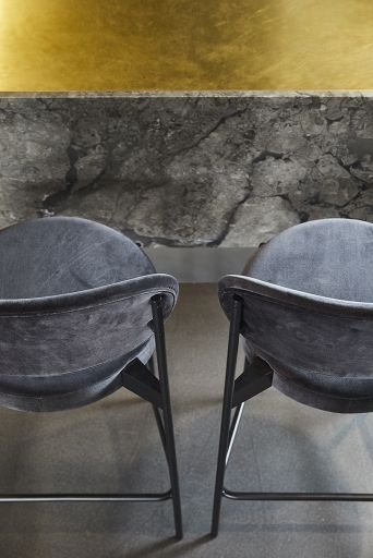 Zwei schwarze Series 430 Barhocker von Verpan mit Remix 123 Bezug vor Marmor-Theke.