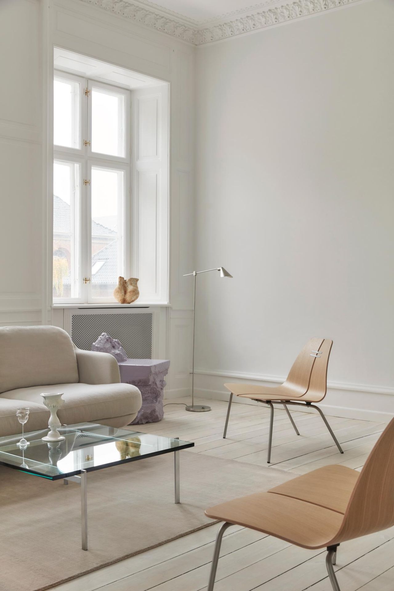 Heller Wohnraum mit Fritz Hansen PK23 Loungesessel aus Holz, Glascouchtisch und Designelementen.