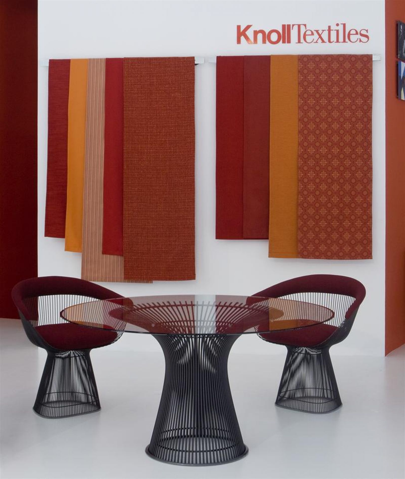 Zwei Platner Sessel von Knoll International in Rot an einem runden Esstisch mit Glasplatte.