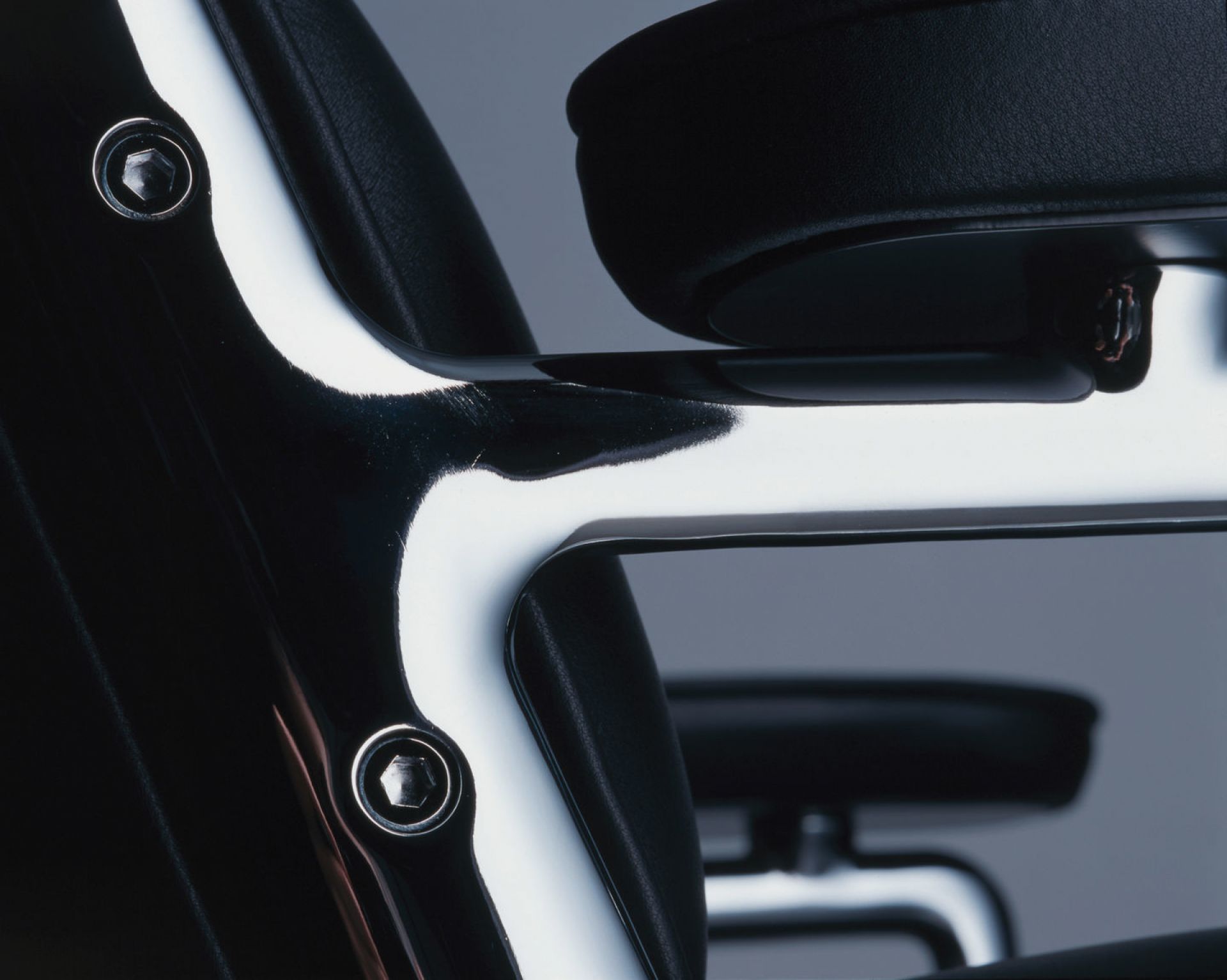 Detailaufnahme des Vitra Lobby Chair ES 104 Stuhls mit schwarzem Leder und Chromgestell.