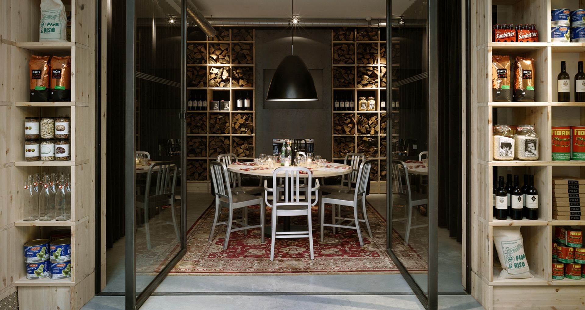 Classic Navy Chair von Emeco, poliertes Aluminium, im Restaurant-Ambiente mit Holzwand und gedecktem Tisch.