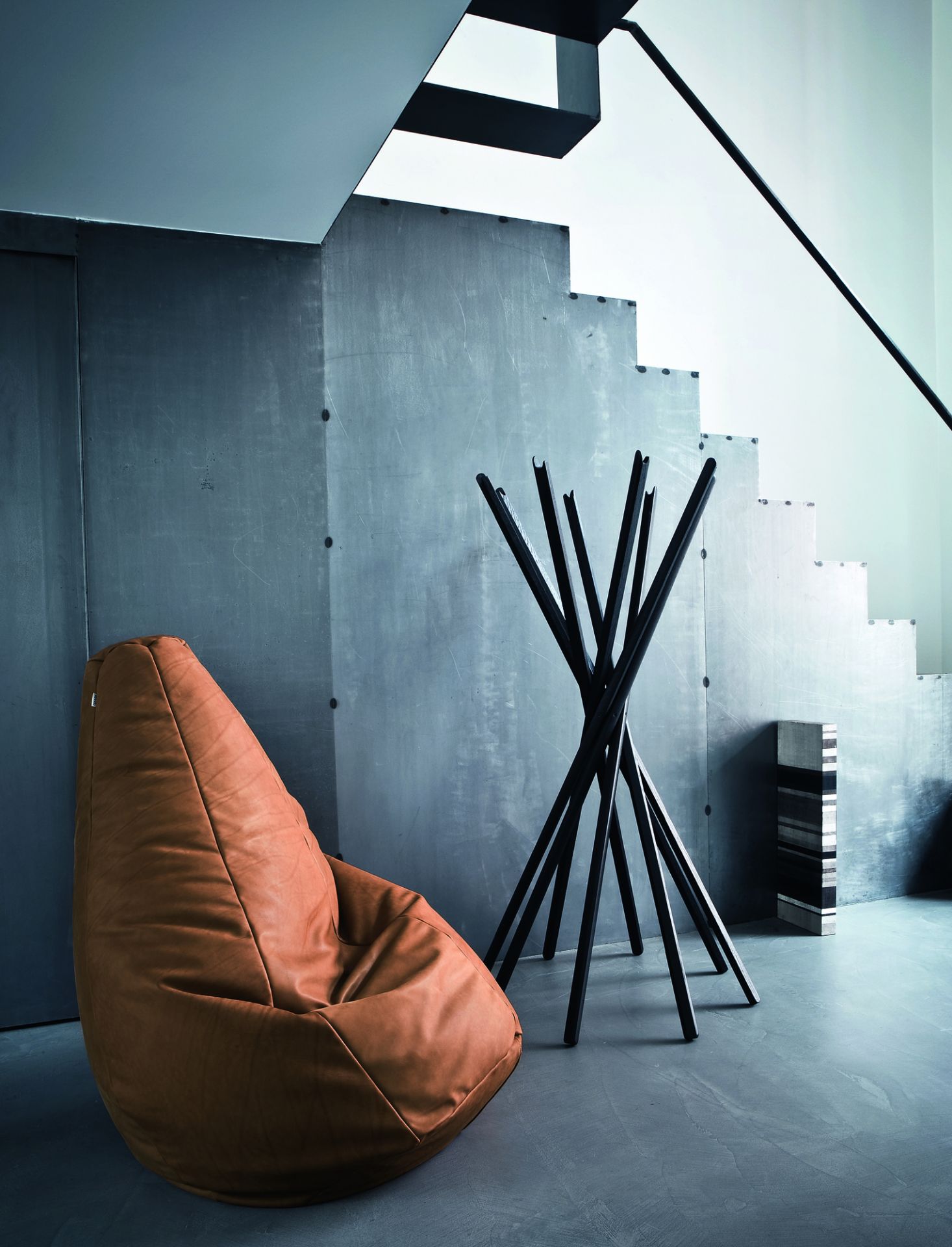 Sciangai Kleiderständer von Zanotta, weiß lackiert, neben einem braunen Sitzsack und einer Treppe. Modernes Design.
