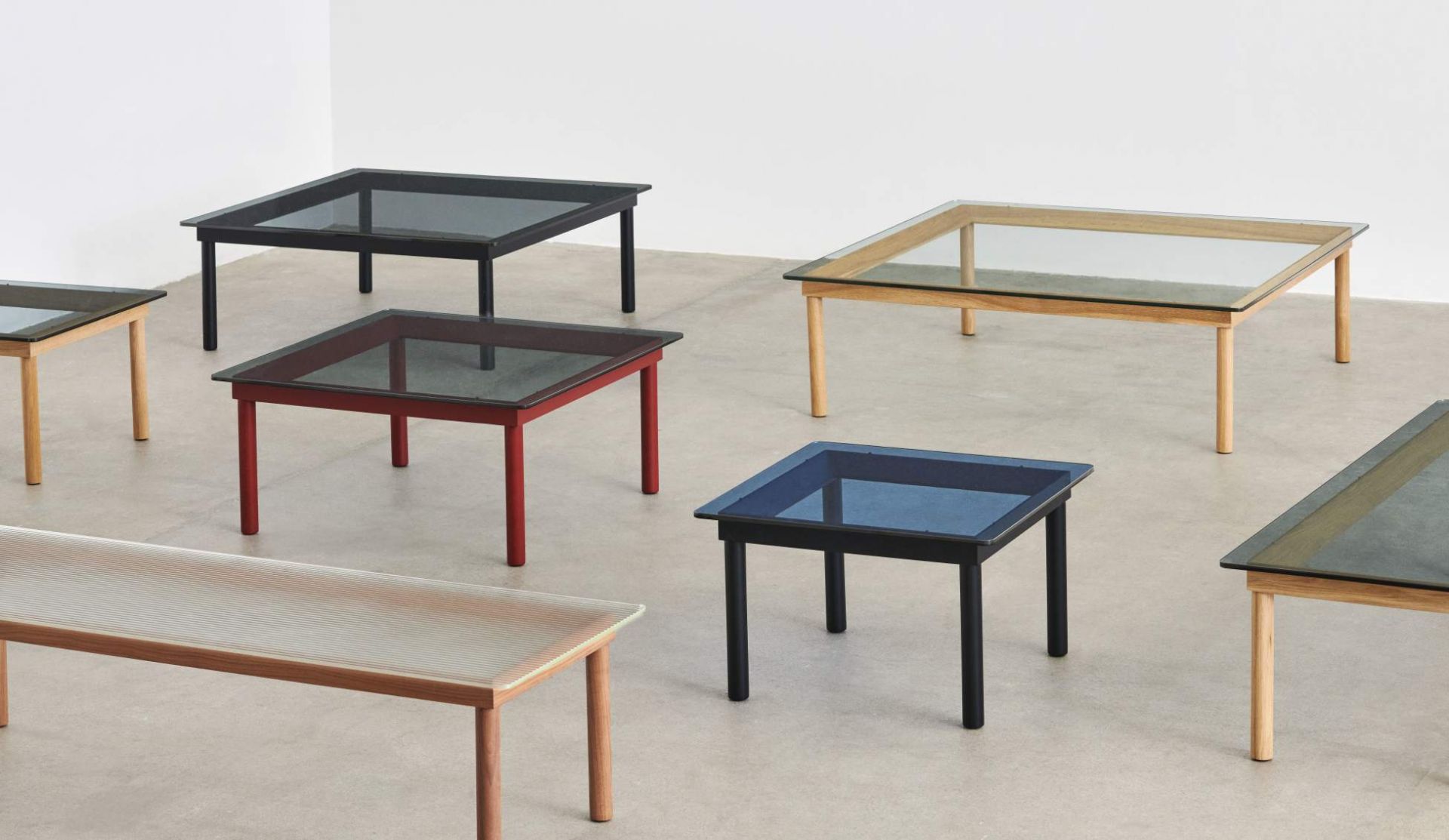 Mehrere Kofi Couchtische von Hay mit Glasplatte und unterschiedlichen Rahmenfarben.