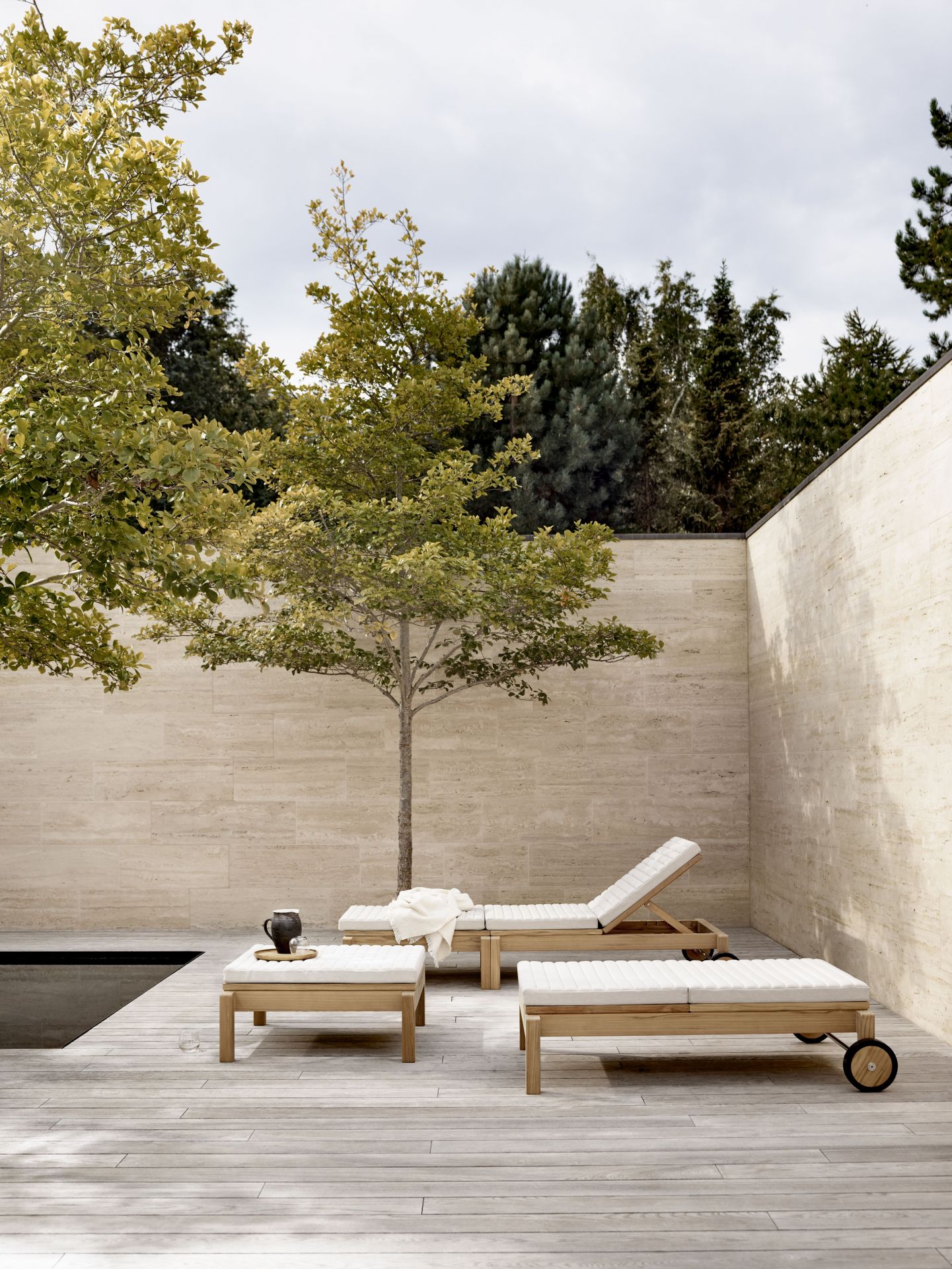 AH604 Teak Gartenliege von Carl Hansen & Søn auf Holzterrasse mit Pool und Bäumen.