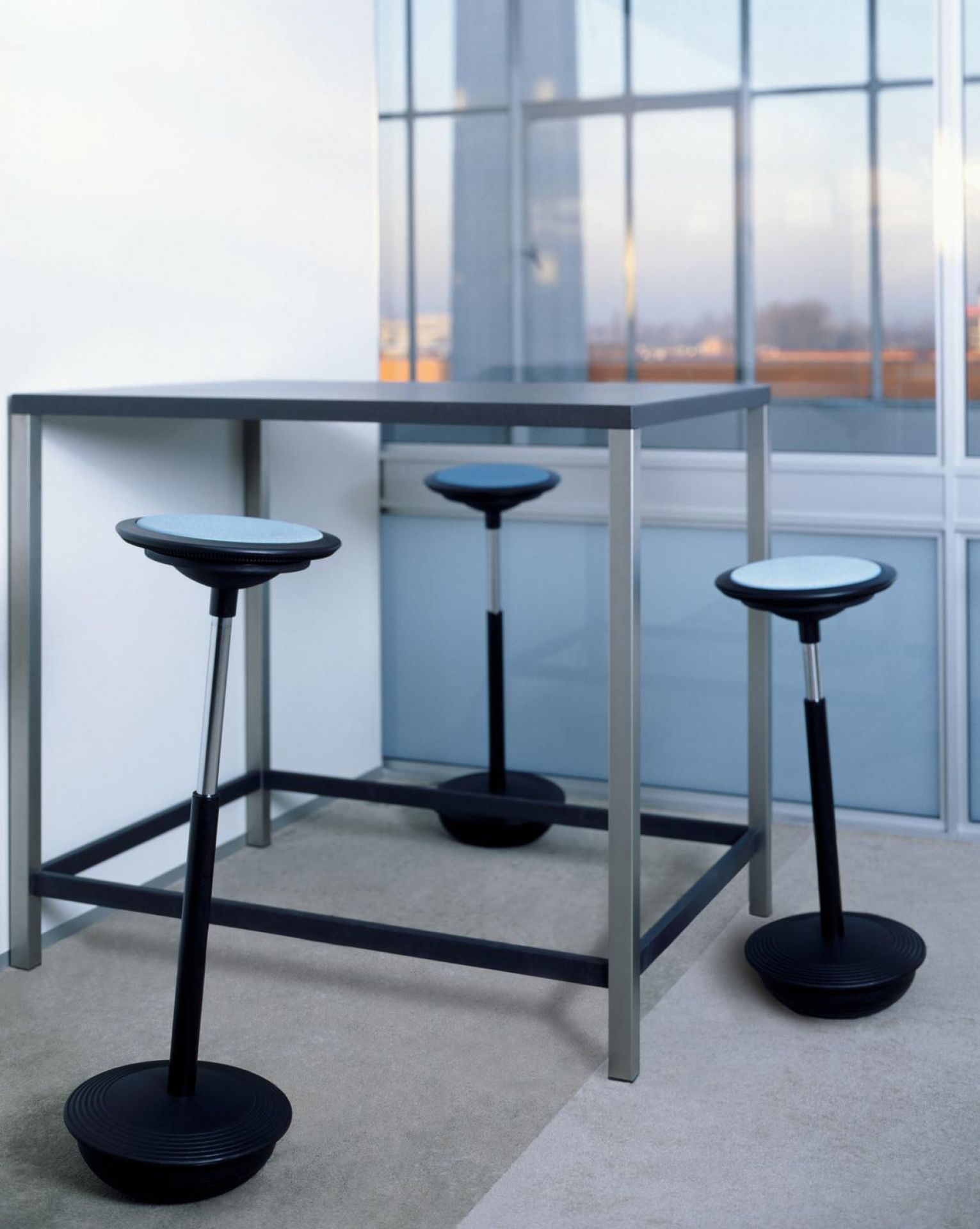 Stitz Stehhocker von Wilkhahn mit blauem Sitzpolster und schwarzem Fuß, ideal für ergonomisches Sitzen.