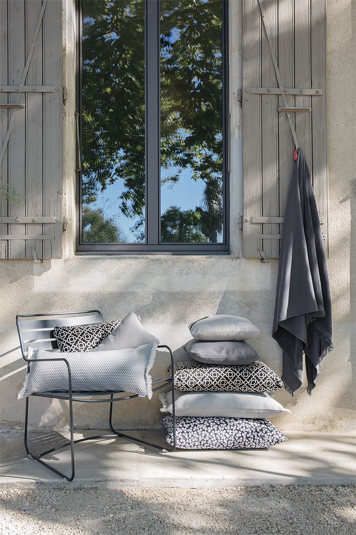 Surprising Fermob Sessel für den Garten mit Kissen und Decke vor Fenster.