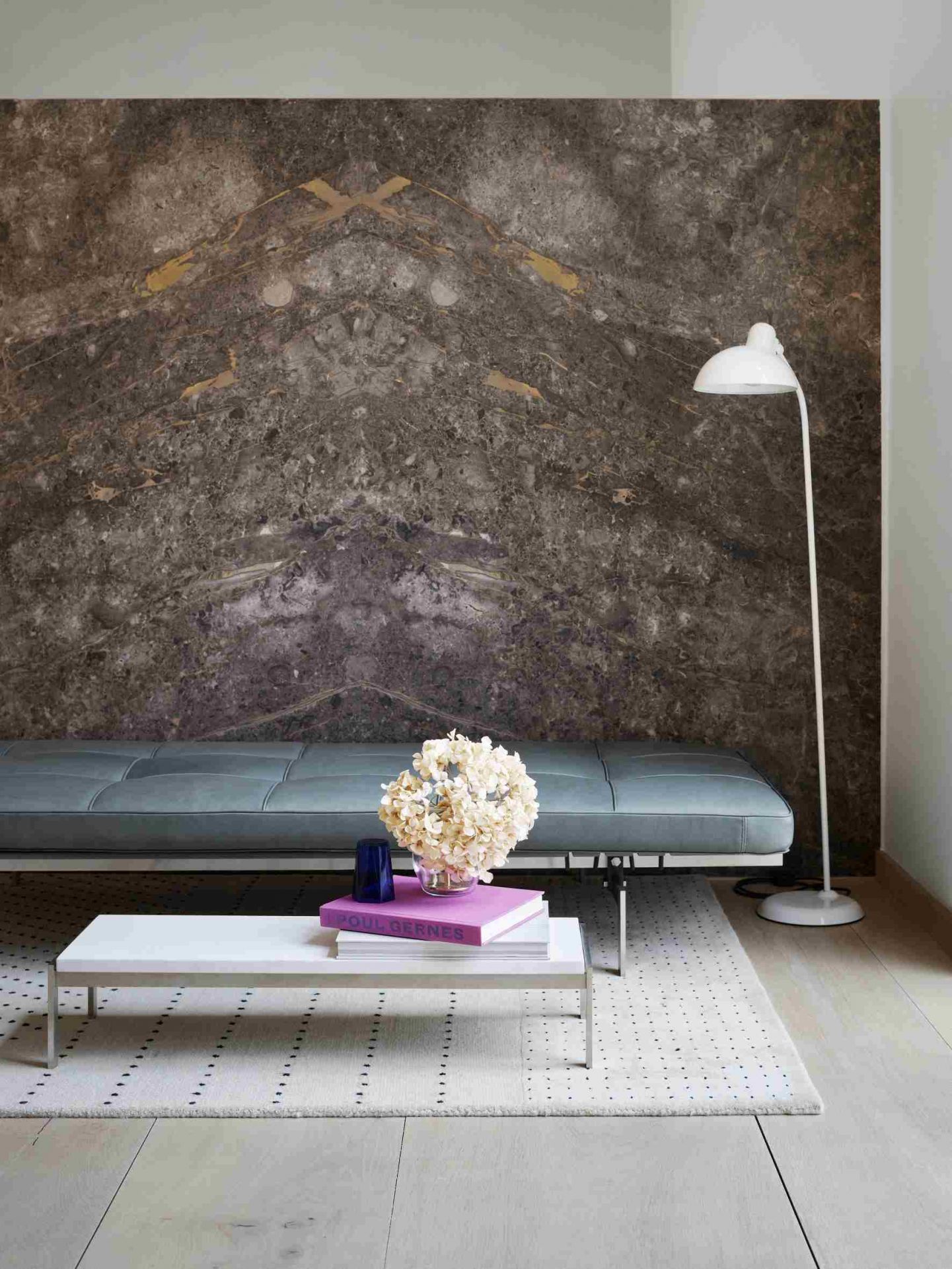 Helle Ledercouch PK 80 von Fritz Hansen im modernen Wohnzimmer mit Marmorwand und Stehlampe.