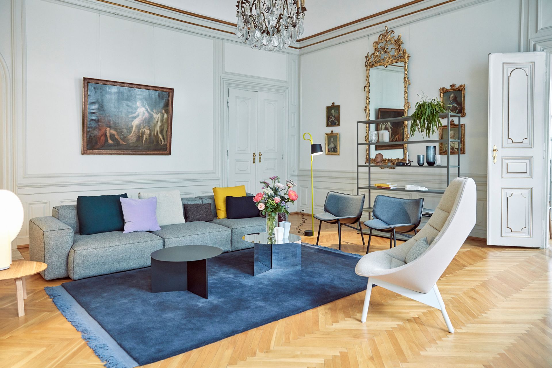 Helles Wohnzimmer mit grauem Hay Mags Soft Sofa, blauem Teppich und Designermöbeln.