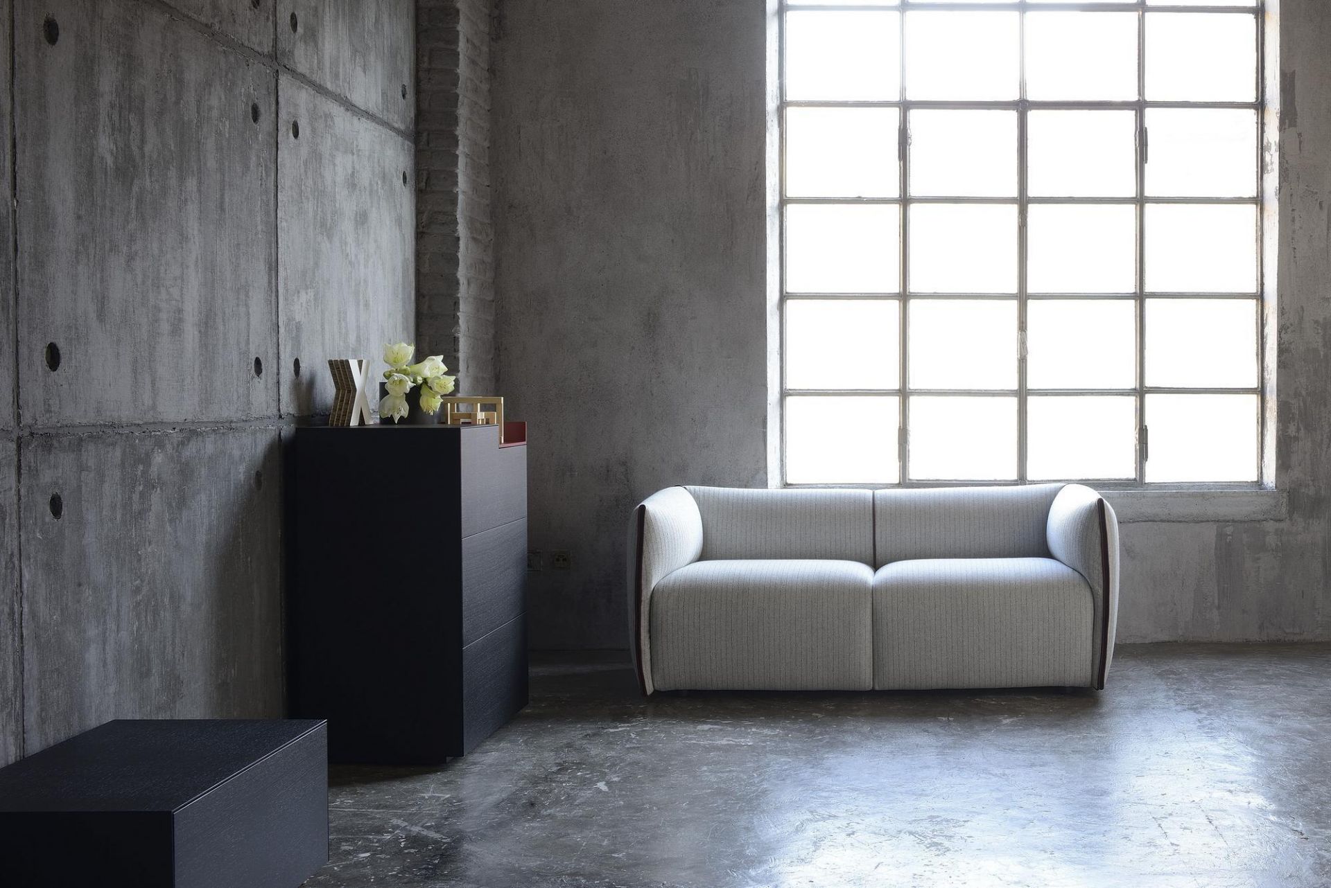 Helles Mia Sofa 2-Sitzer von MDF Italia in modernem Wohnzimmer mit Betonwand und Fenster.