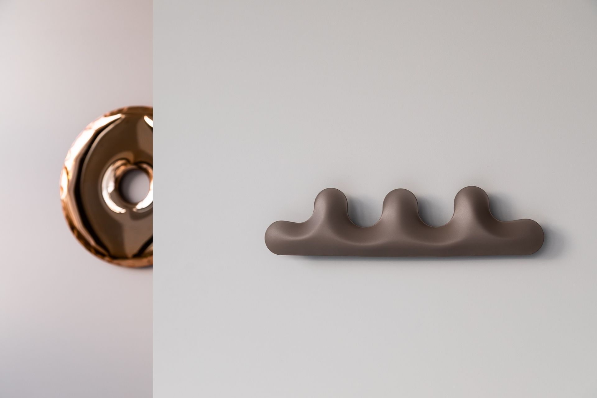 Kamm Garderobe Zieta, braun, an einer Wand befestigt, daneben ein runder goldener Kleiderhaken.