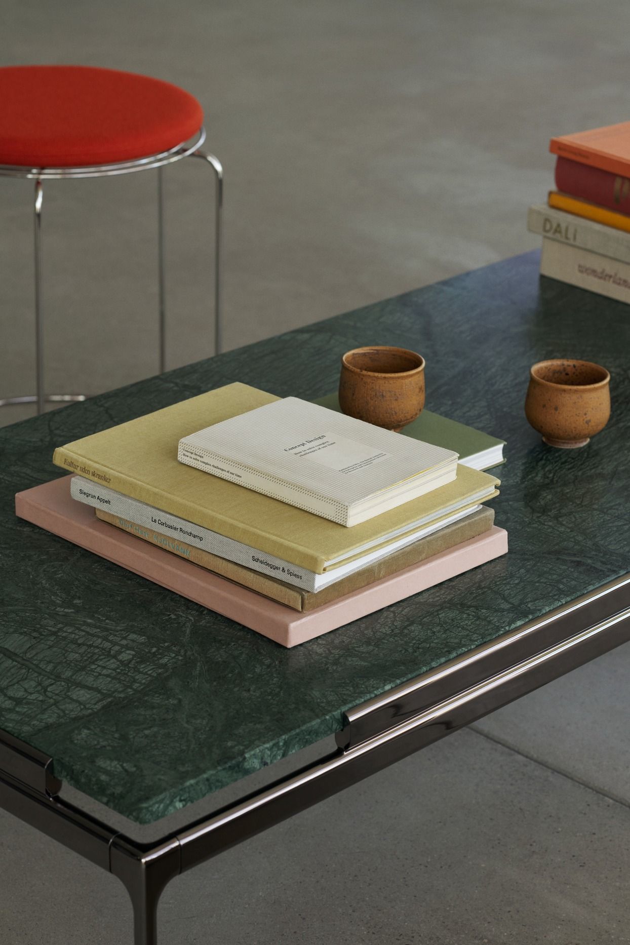 AndTradition Sett Couchtisch mit grüner Marmorplatte, Büchern und Keramikbechern dekoriert. Moderner Wohnzimmertisch.