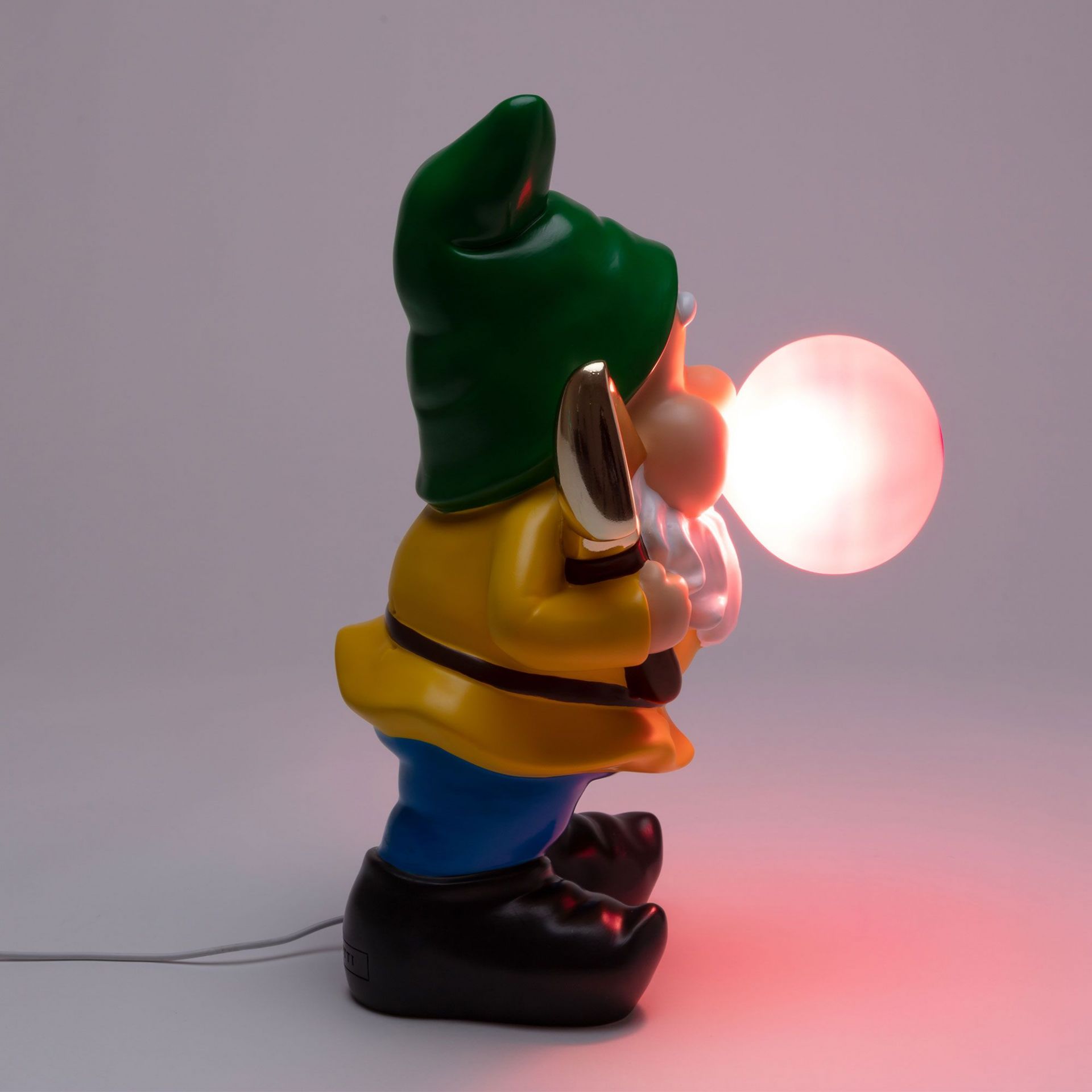 Seletti Gummy Working Lampe: Detailaufnahme eines Gartenzwergs mit grüner Mütze, der eine leuchtende Kugel hält.