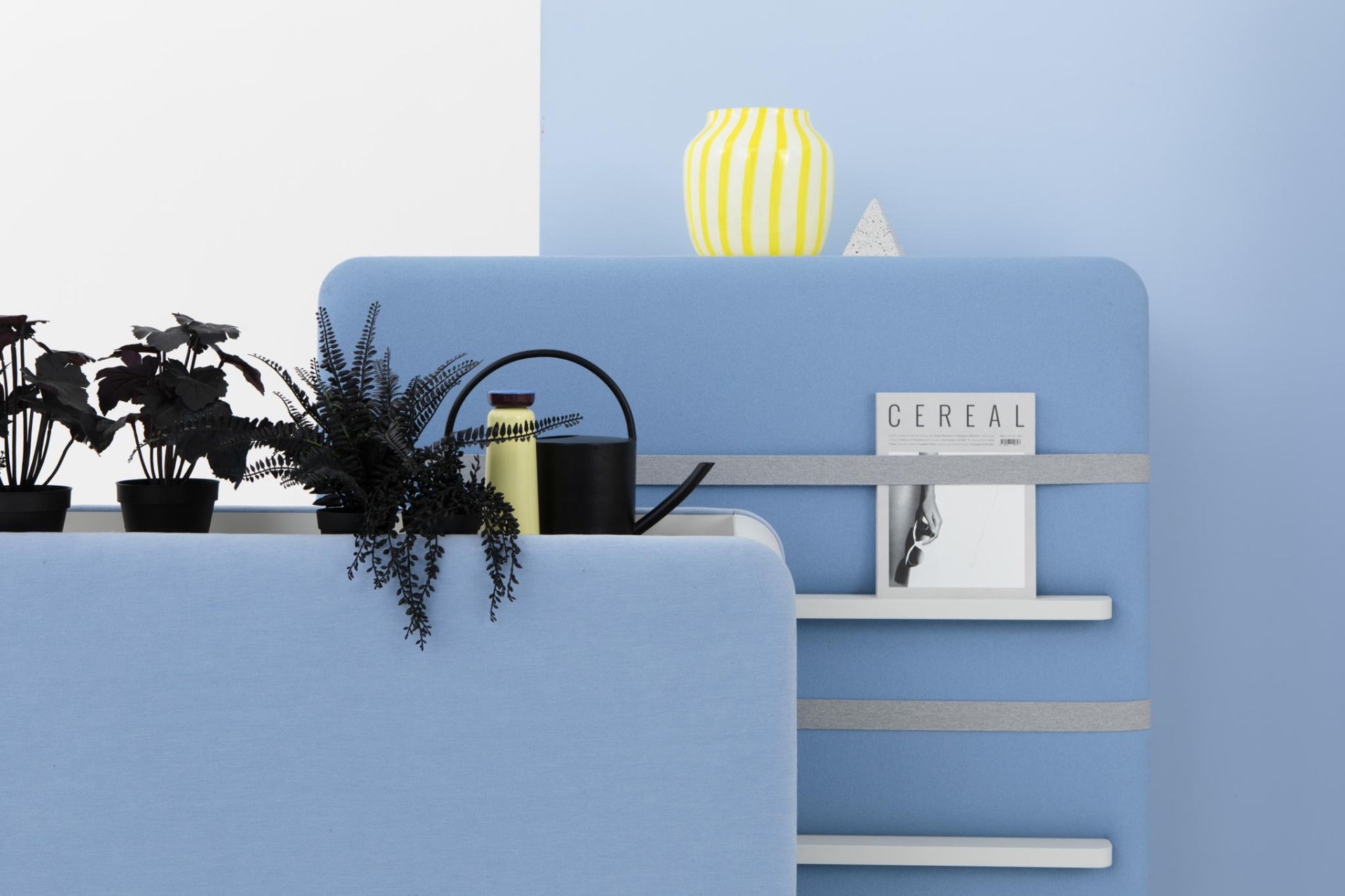 Cascando Pillow Space Akustik-Raumteiler in Hellblau mit Pflanzen, Gießkanne und Regalen für Büro oder Wohnraum.