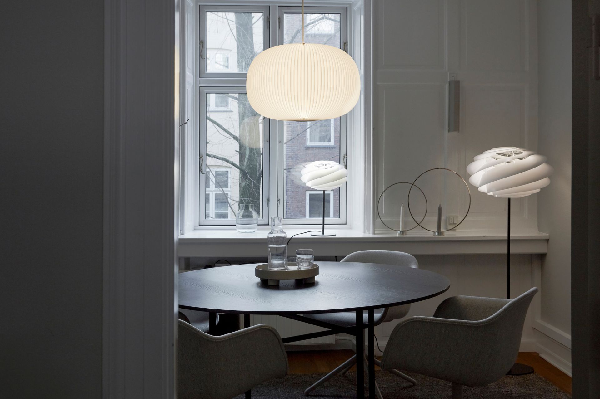 Helle Lamella Pendelleuchte von Le Klint über Esstisch in modernem Esszimmer mit Fenster.