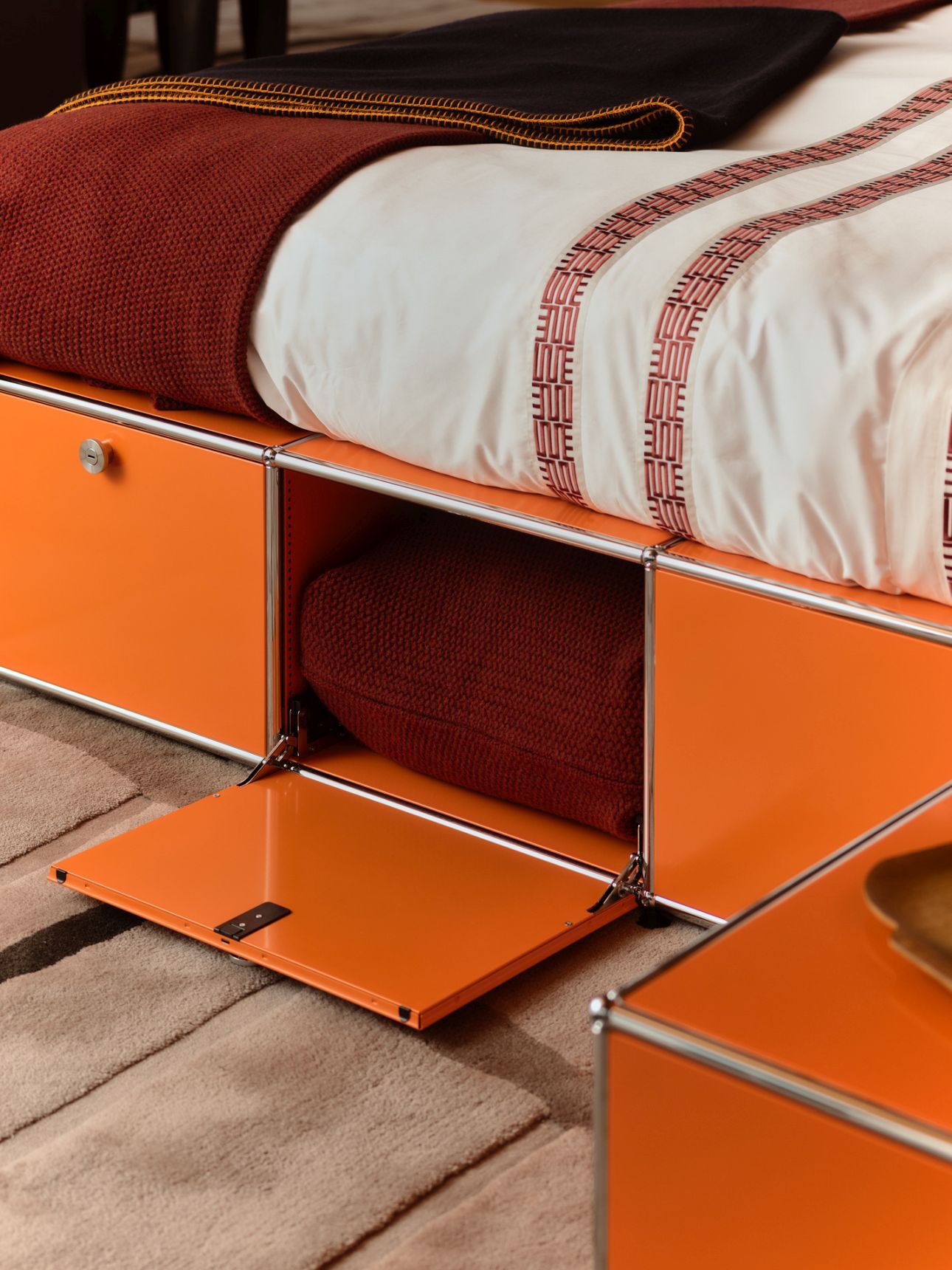 USM Haller Bett Mansa von Armando Cabral in Orange mit Bettwäsche und Stauraum.