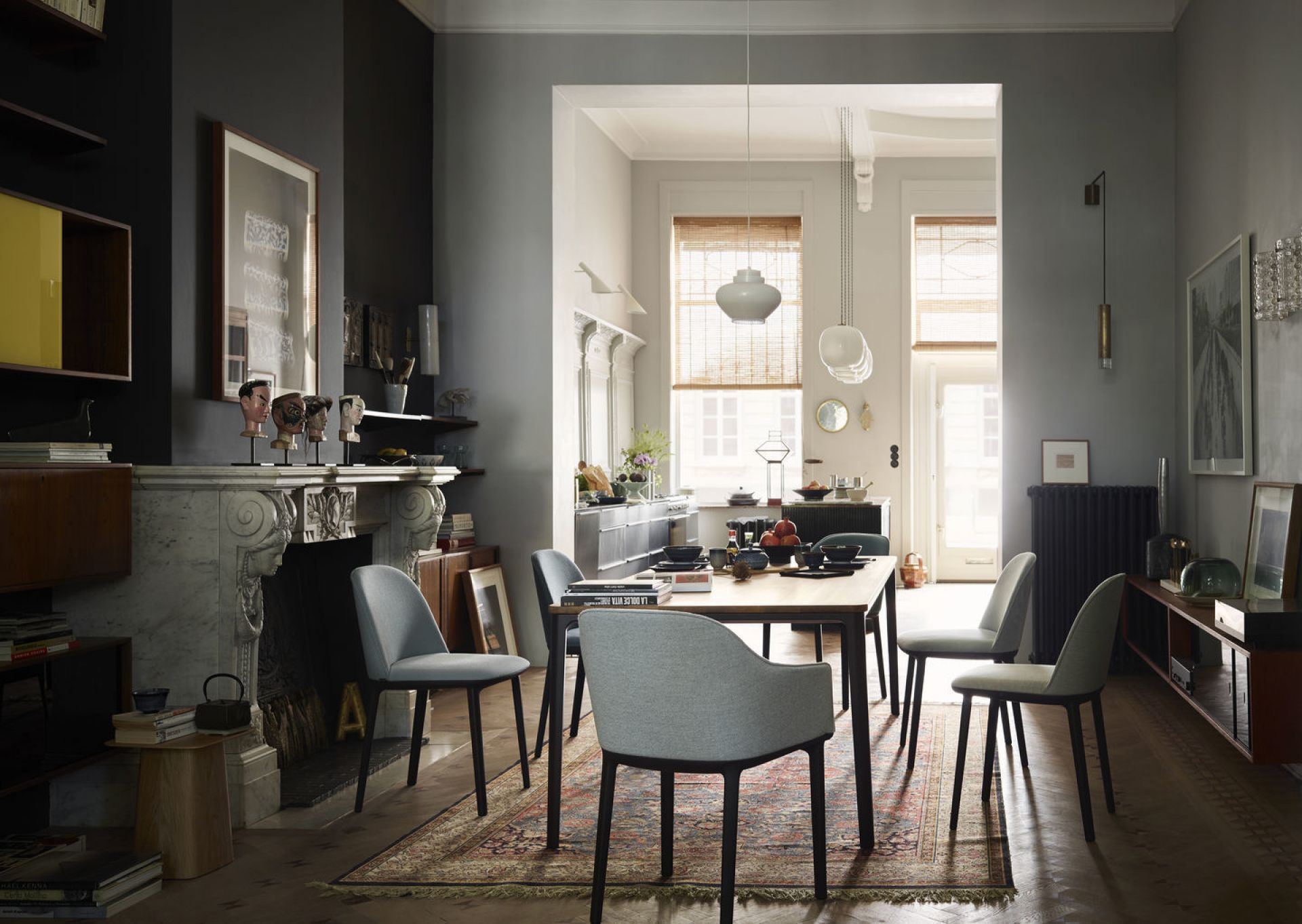 Esszimmer mit Esstisch und sechs hellgrauen Softshell Side Chairs von Vitra mit dunklen Beinen.