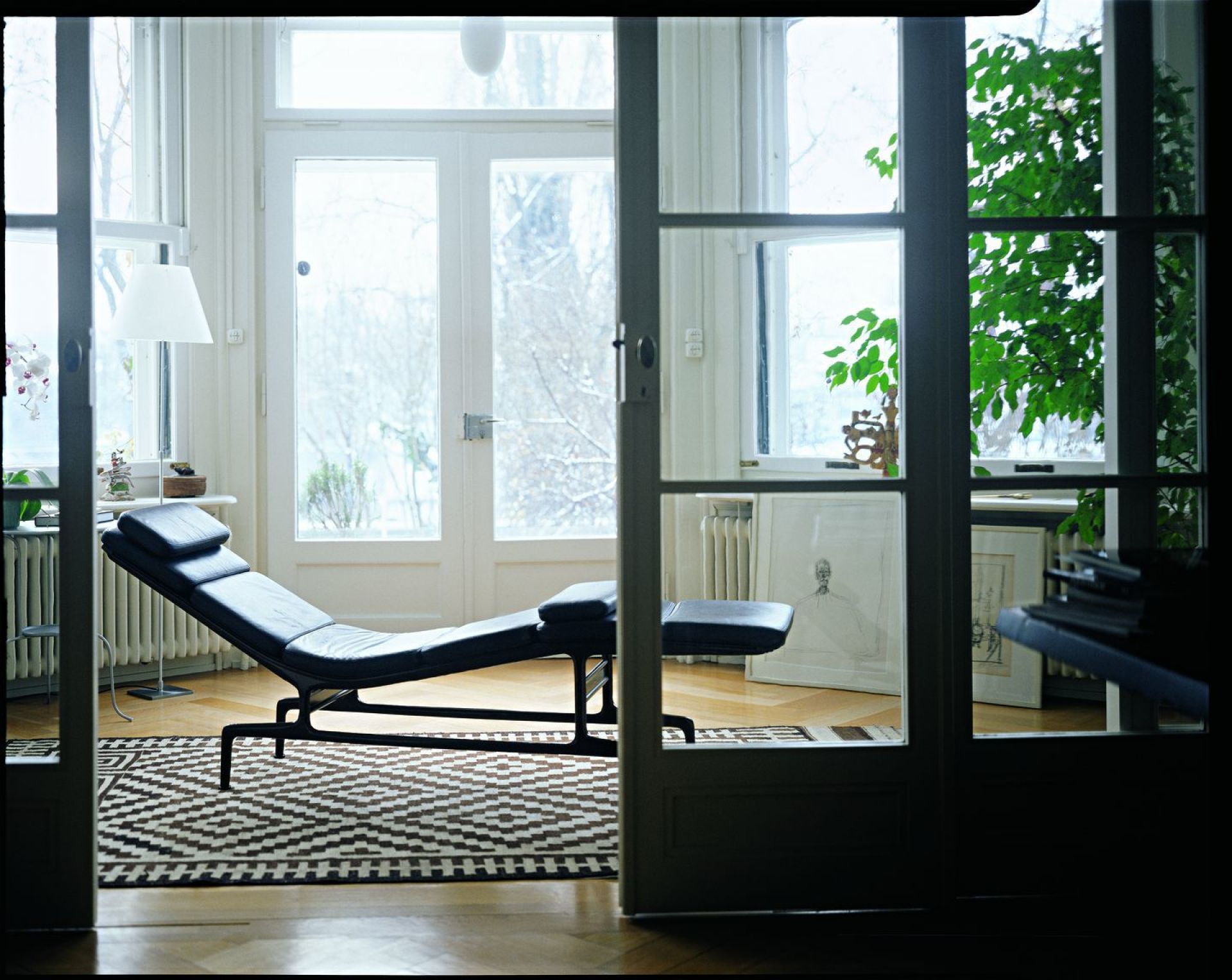 Schwarze Soft Pad Chaise Liege von Vitra im hellen Raum mit Teppich und Fensterfront.