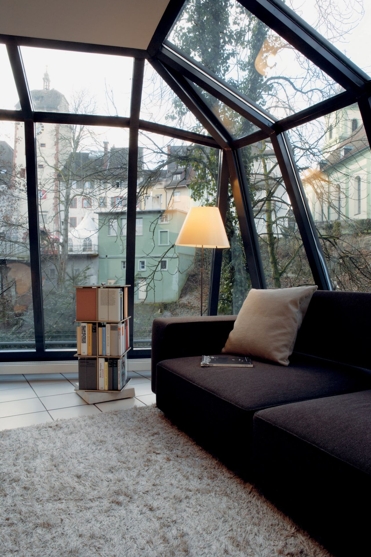 Nils Holger Moormann Buchstabler Bücherregal im modernen Wohnzimmer mit Sofa und großem Fenster.