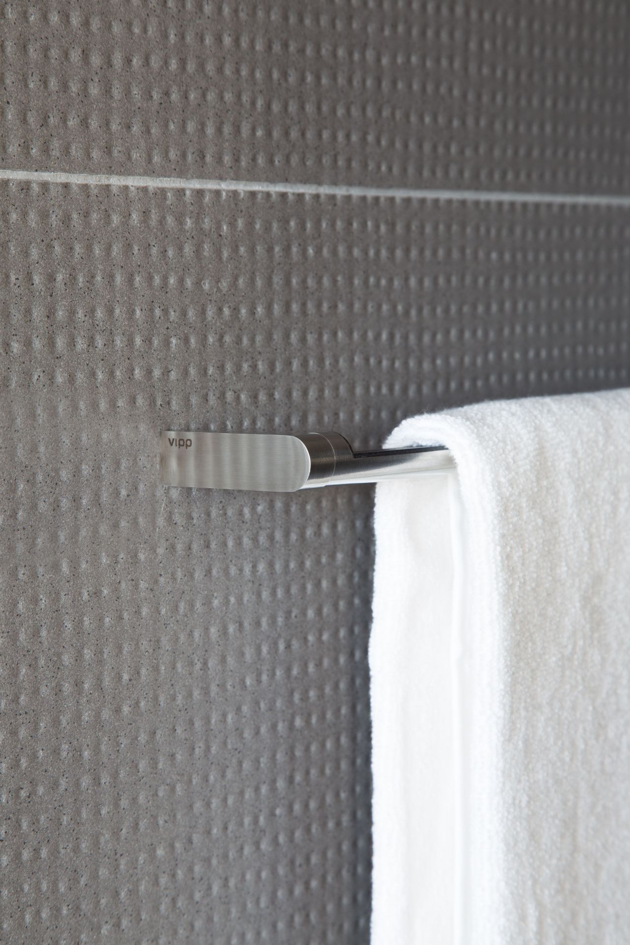Nahaufnahme einer Vipp Handtuchstange aus Edelstahl mit weißem Handtuch im Badezimmer.