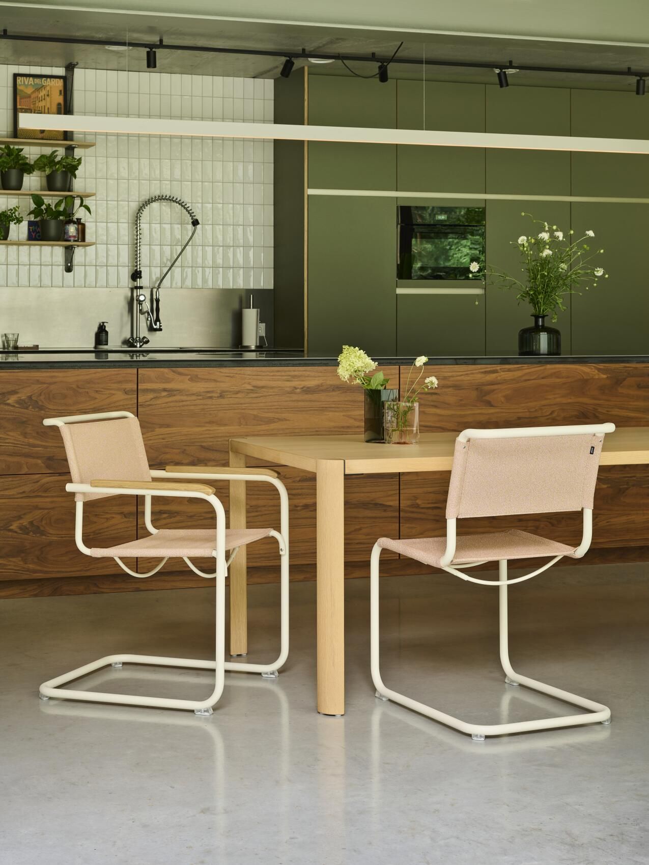 Zwei Thonet S 33 V Freischwinger Stühle mit beigem Stoffbezug und weißem Stahlrohrgestell am Esstisch.