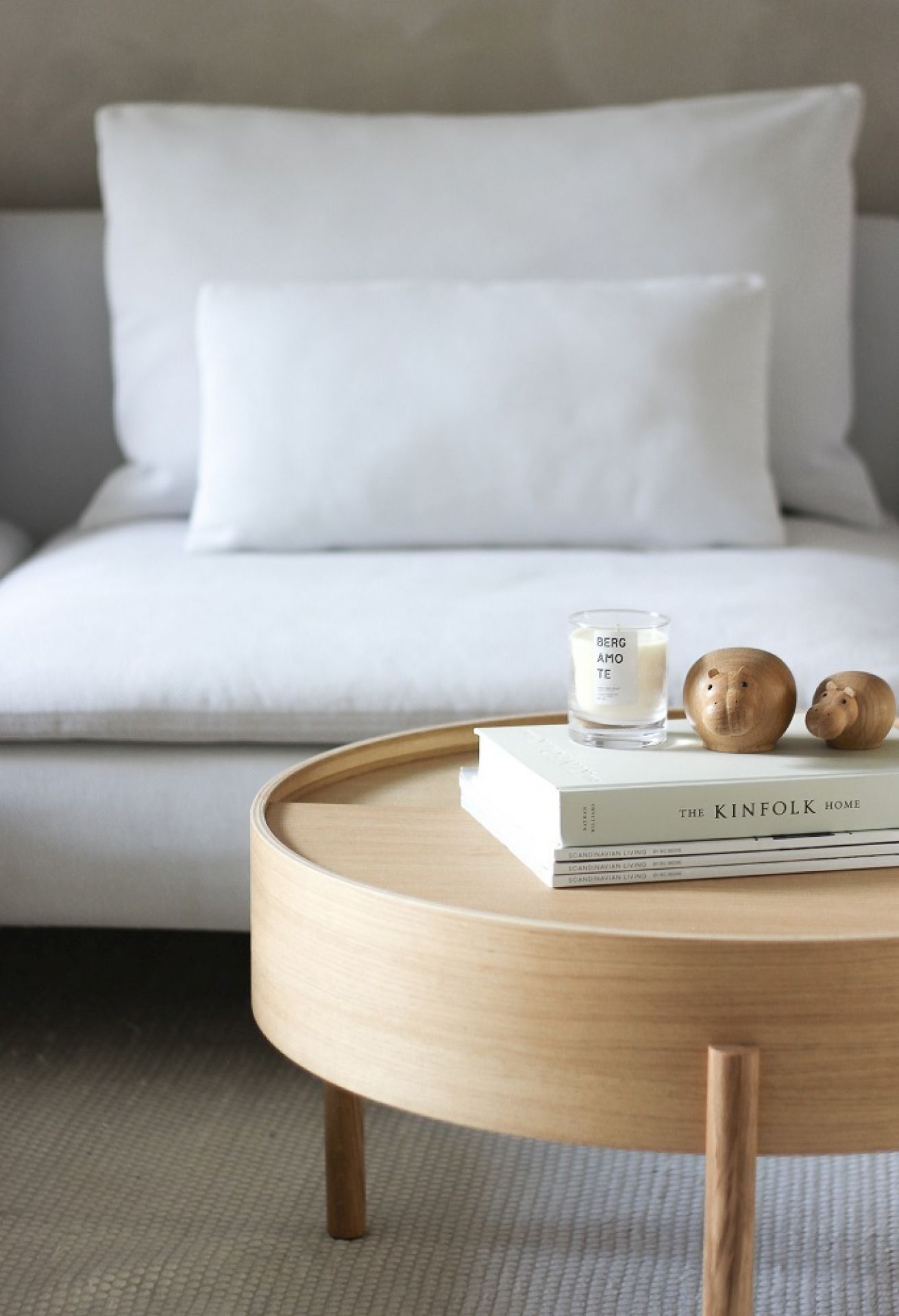 Runder Couchtisch aus Eiche geölt von Woud, mit Deko-Elementen auf einem Sofa.